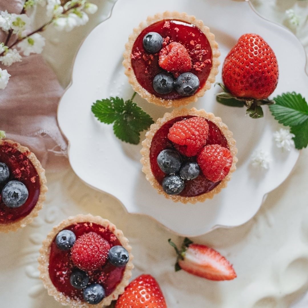 Three cupcakes with strawberries and blueberries on a white plate