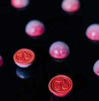 A group of pink balls with hearts on them are sitting on a black surface.