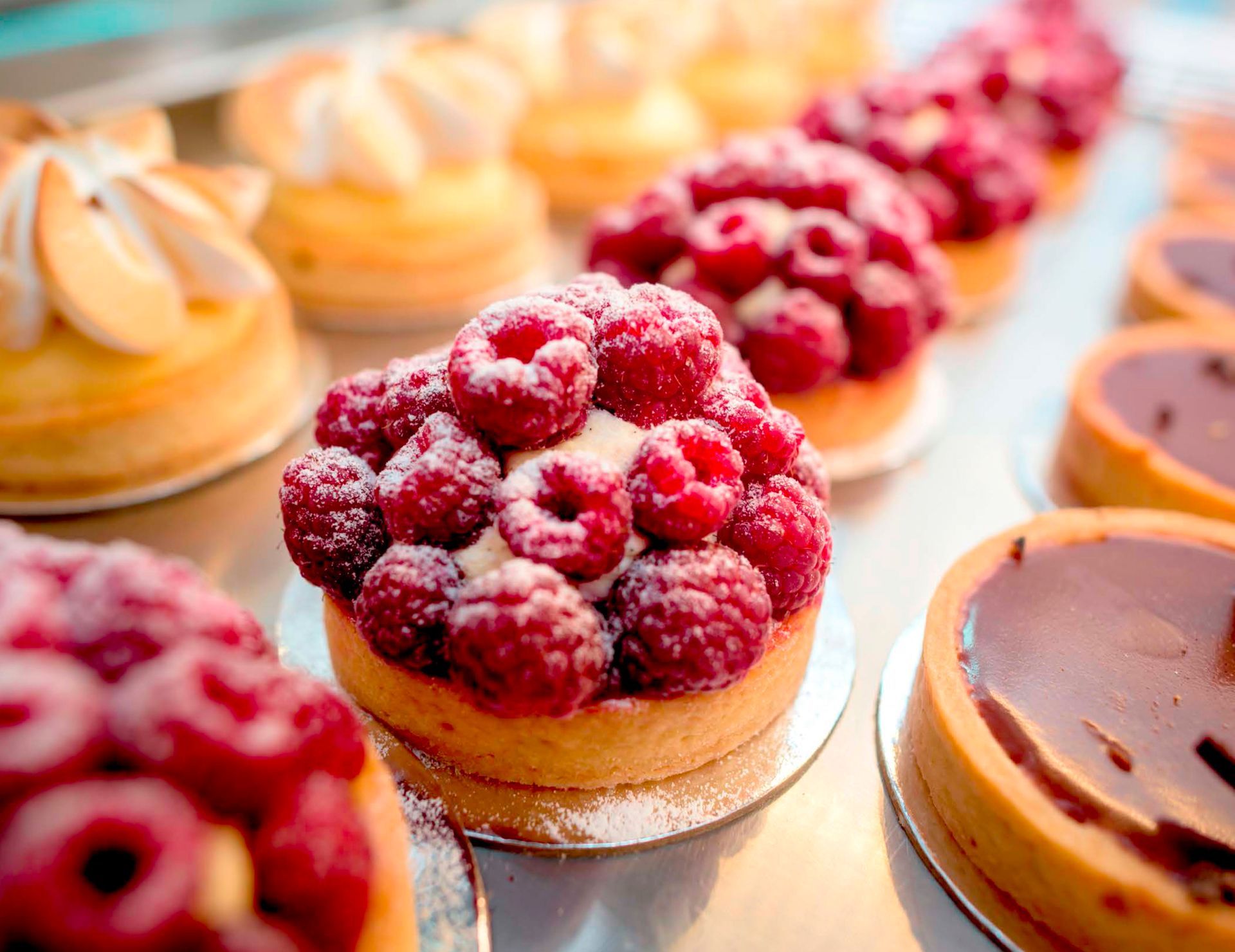 A row of desserts with raspberries on top of them on a table.
