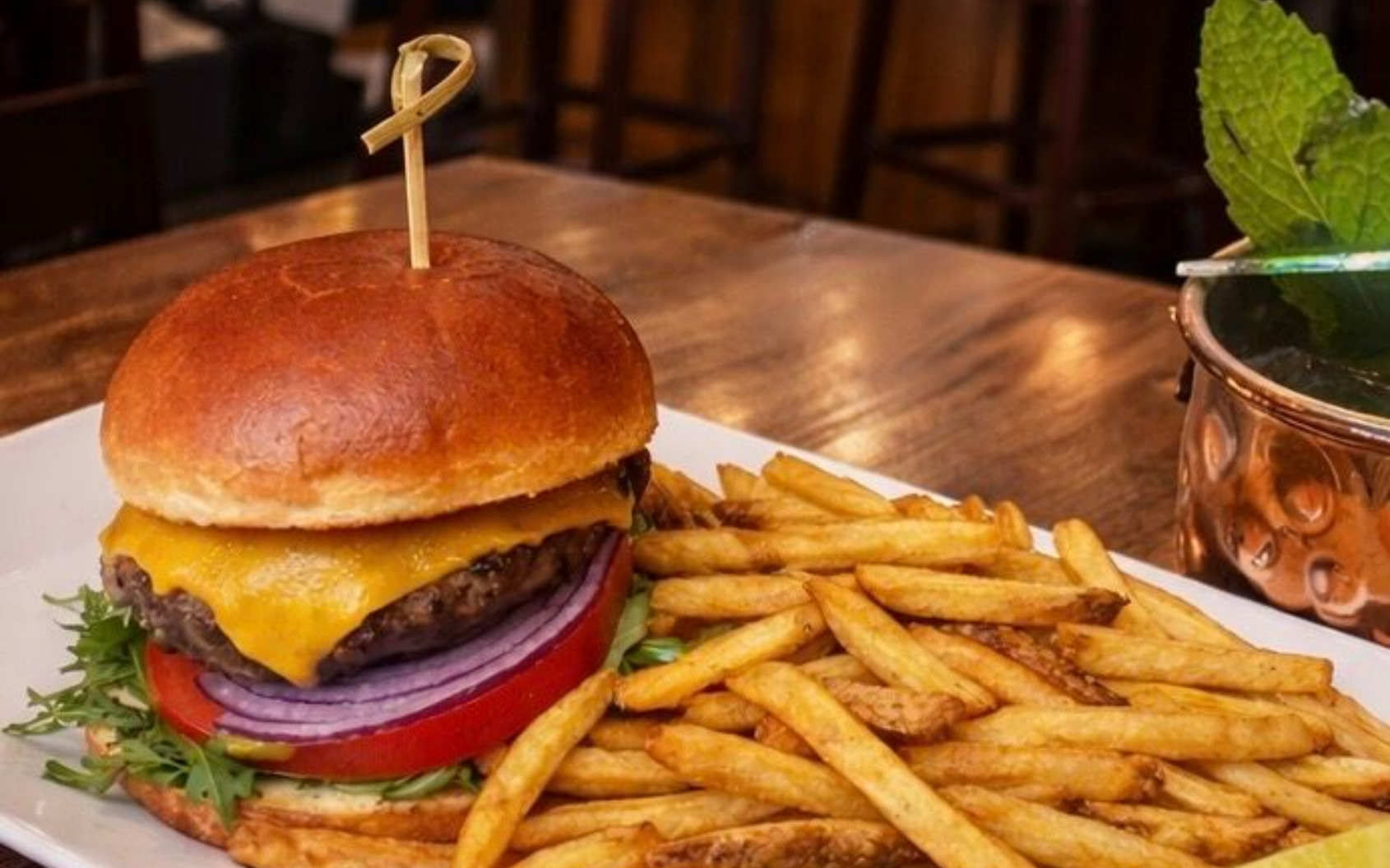 Cheeseburger with fries on a wooden table in a restaurant