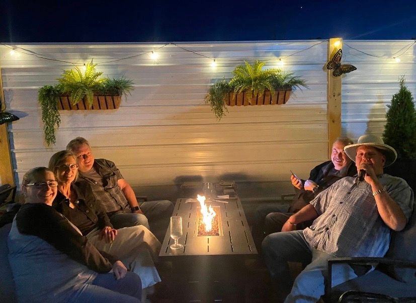 People sitting around a lit fire pit on a backyard patio at night