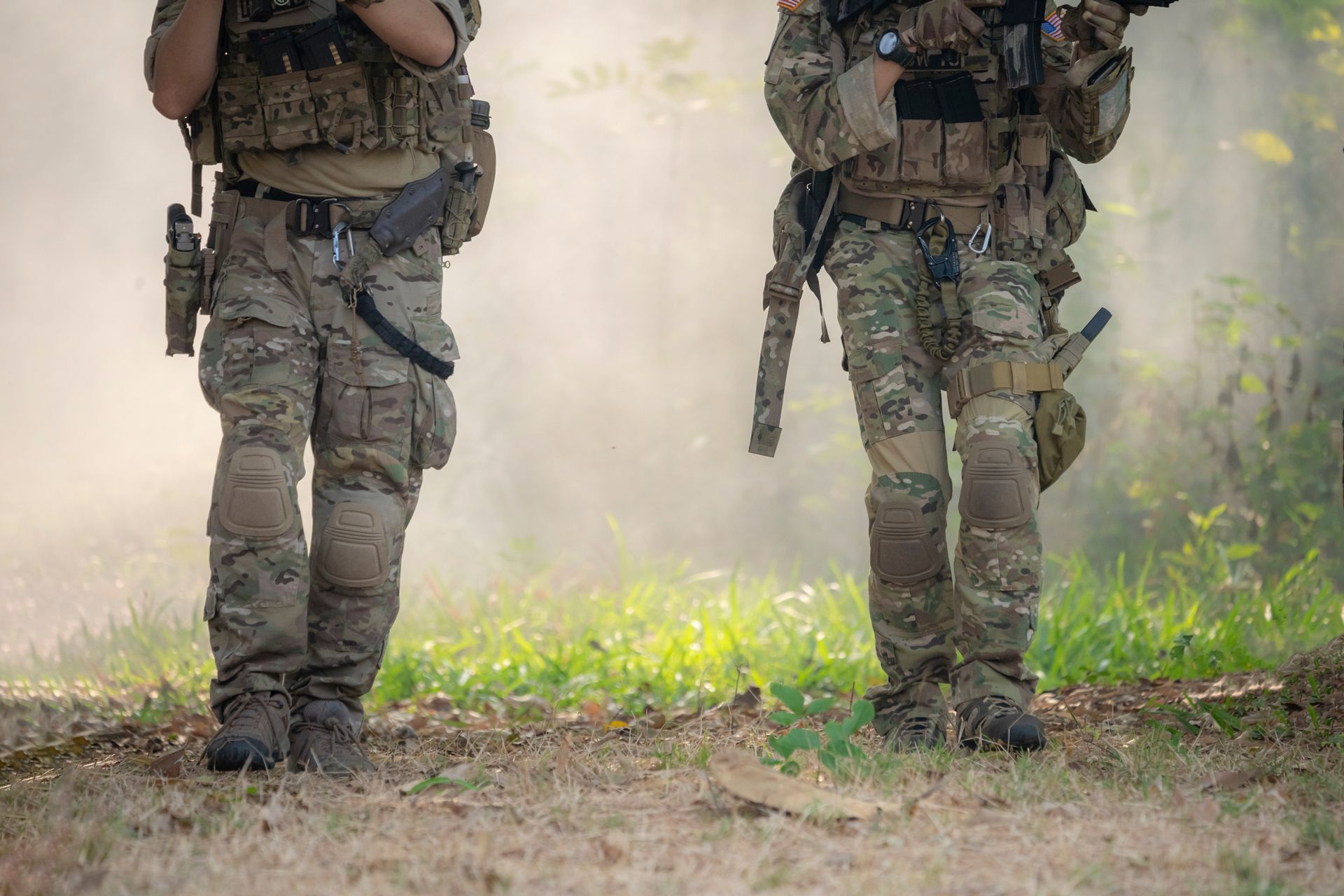 Two soldiers in camouflage gear stand in a smoky forest.