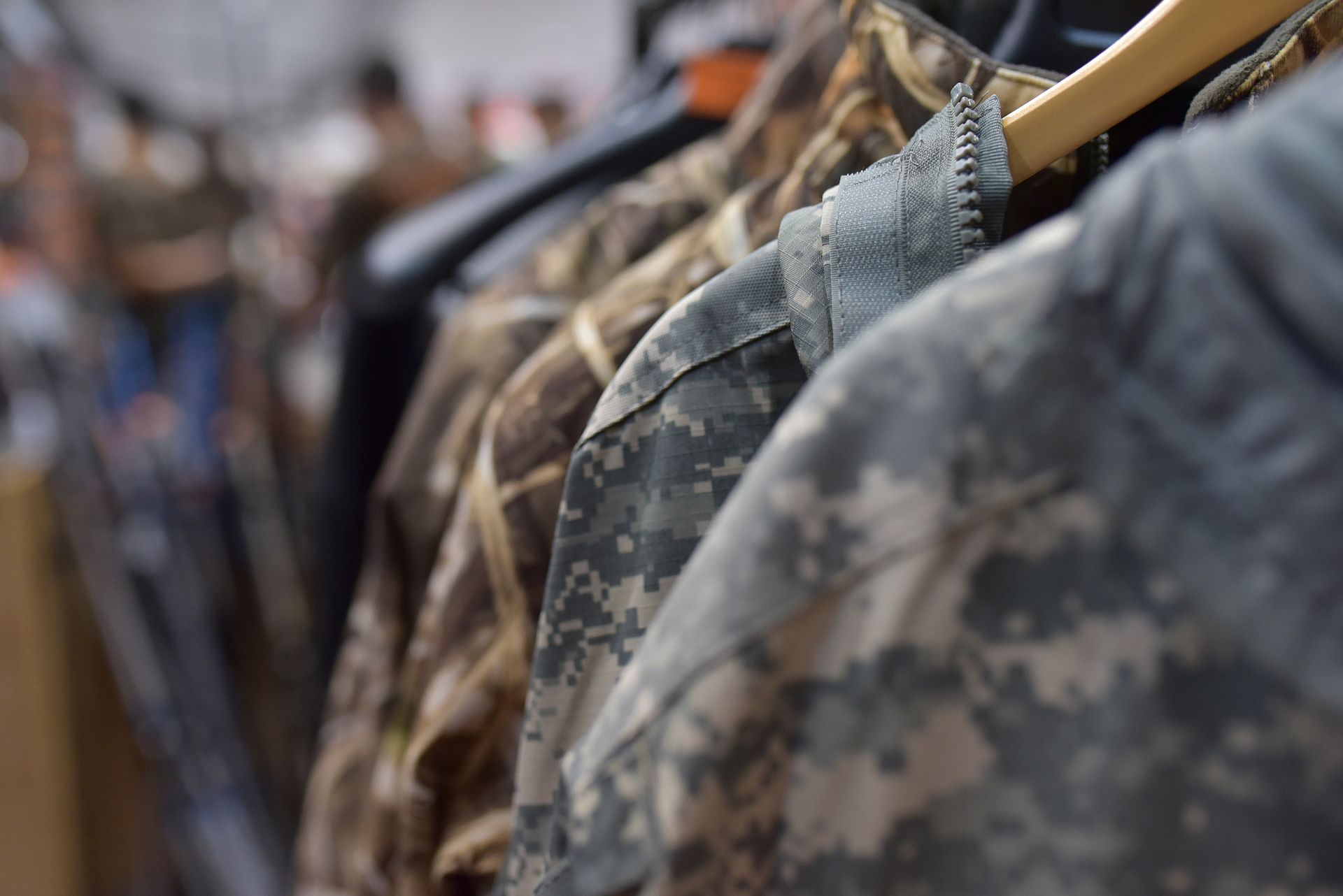 Camouflage jackets hanging on a rack in a store, variety of patterns visible.