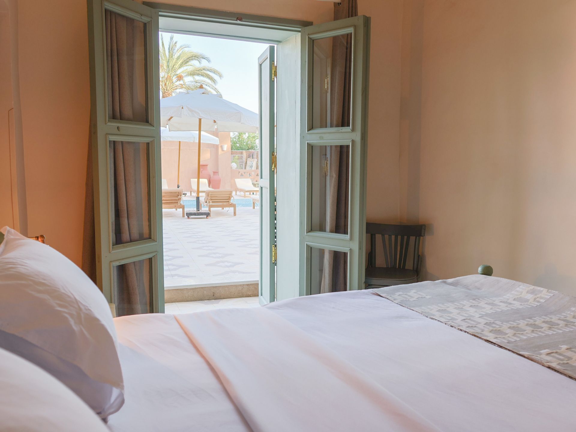 Bedroom doorway open to a patio with lounge chairs and umbrellas.