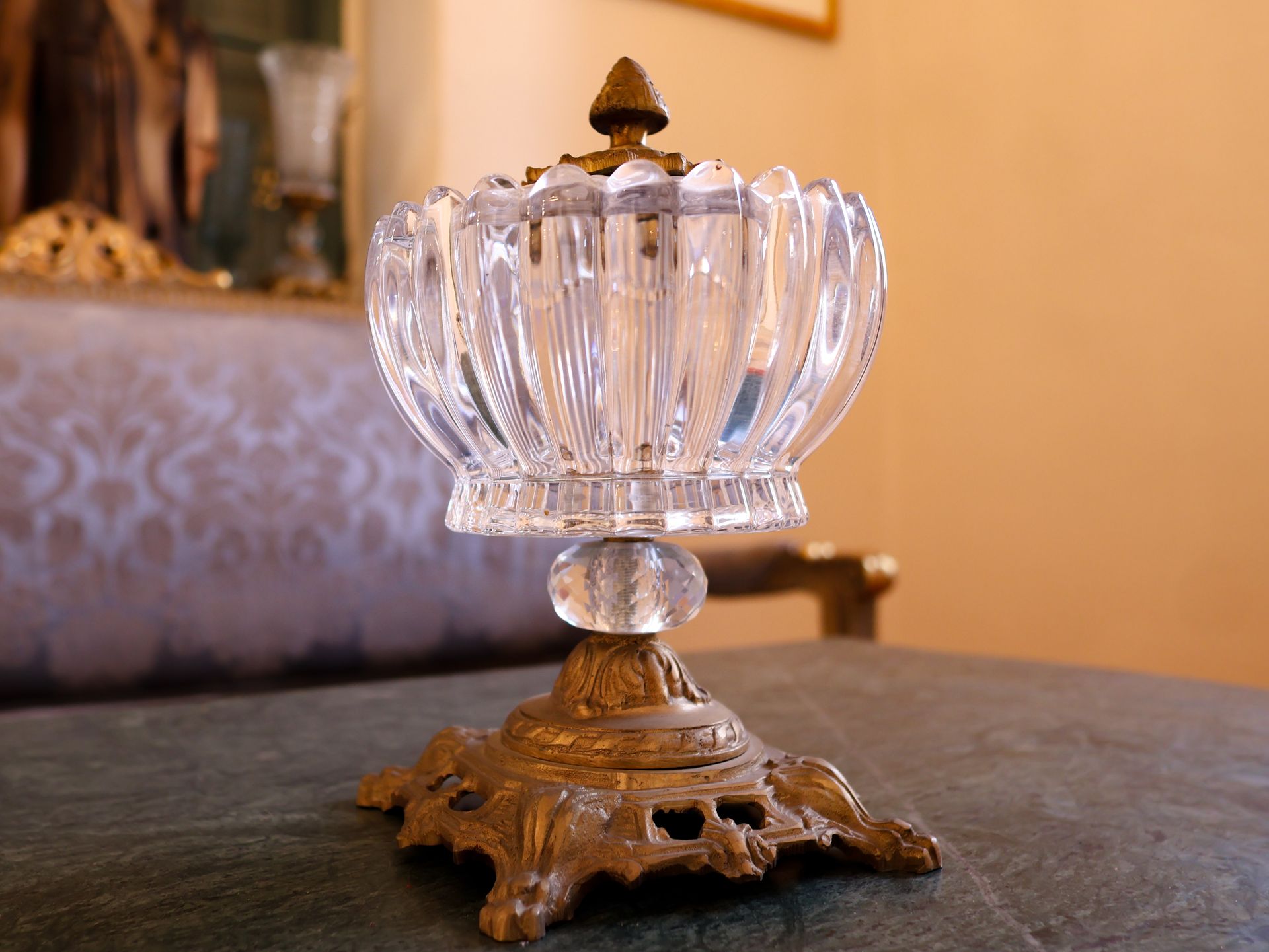 Crystal and brass candy dish on a patterned cushion.