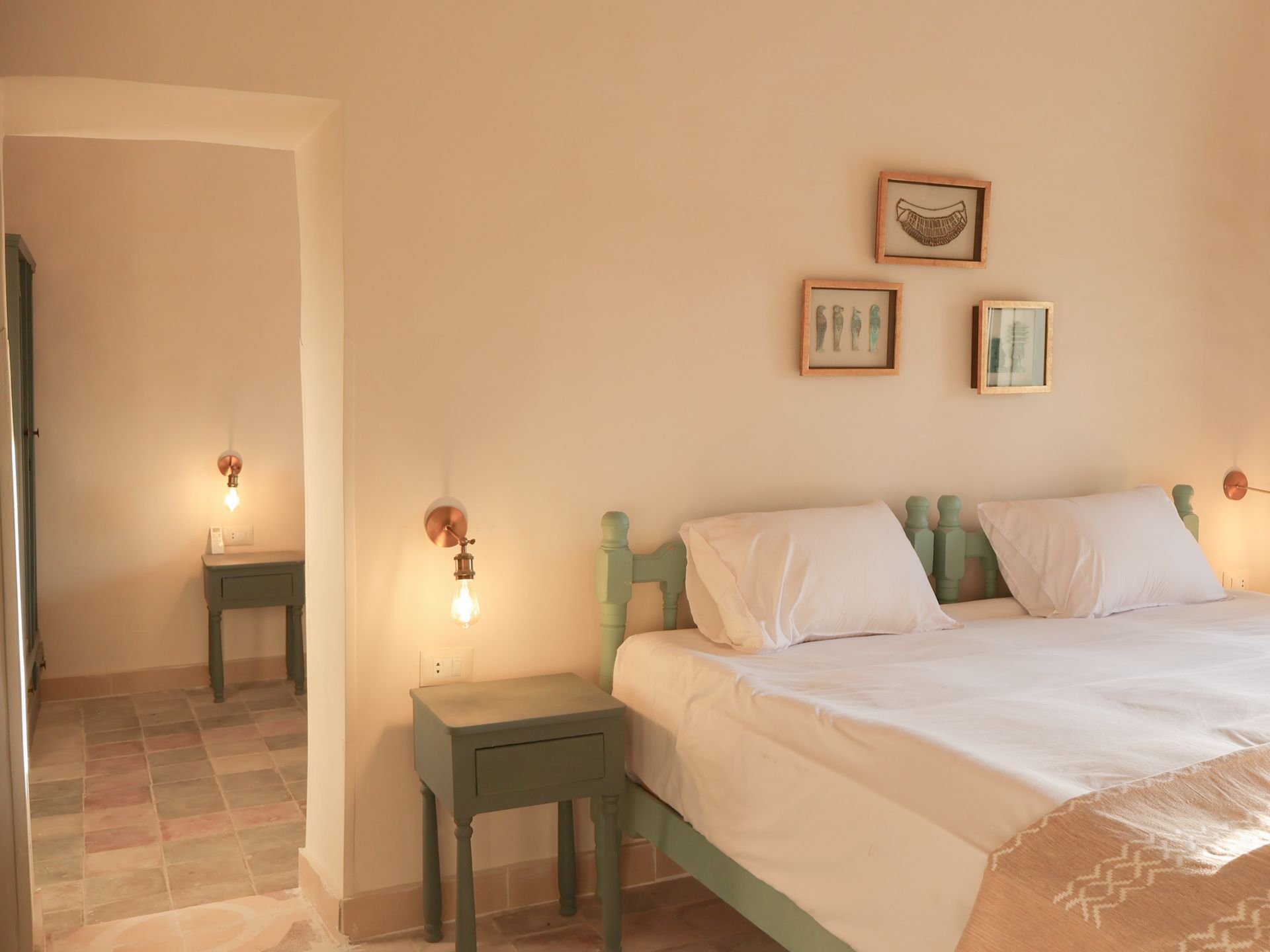 Bedroom with a light green bed frame, matching nightstands, and wall-mounted lights. Pale pink walls.