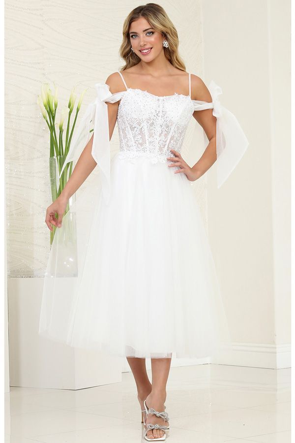 Woman in white formal dress with tulle skirt and shoulder bows, smiling.