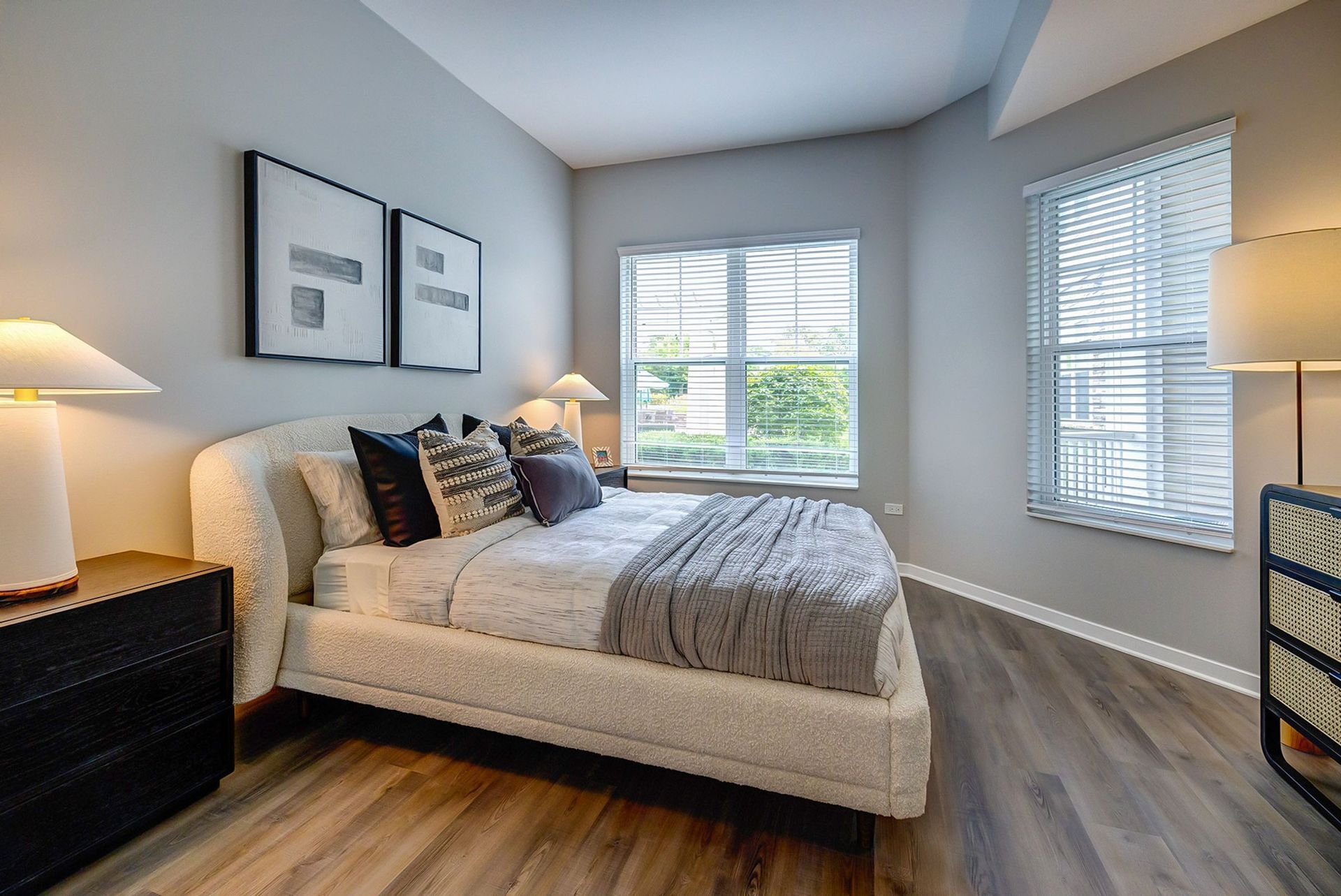A bedroom with a bed , nightstand , lamps and a window.