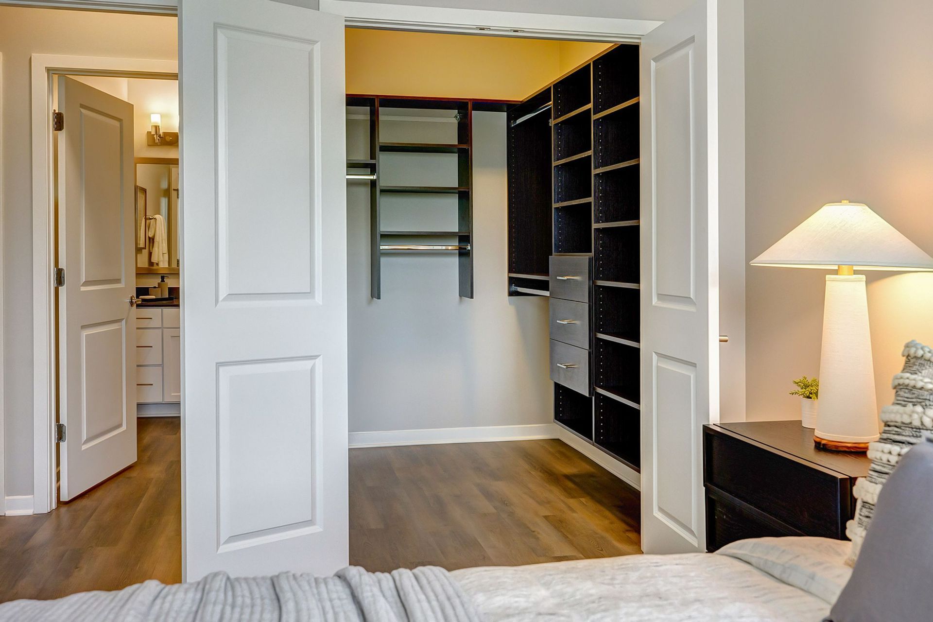 A bedroom with a walk in closet and a lamp.