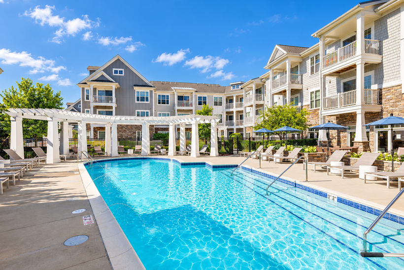 A large swimming pool in front of a large apartment building.