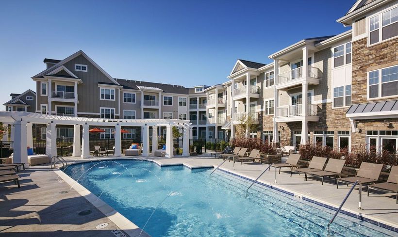 A large swimming pool in front of a large apartment building.