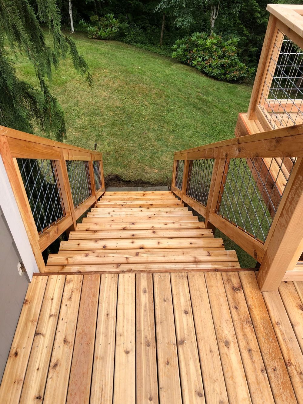 Wooden deck and stairs leading down to a grassy yard.