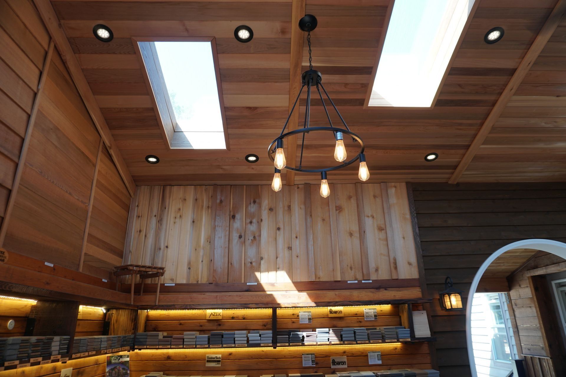 Wooden interior with skylights, chandelier, recessed lighting, and a partially arched doorway.
