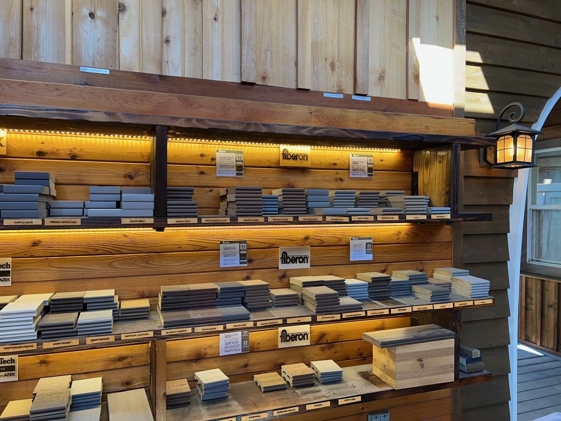 Wooden display shelves holding various stone tiles with labels, lit by warm lights.