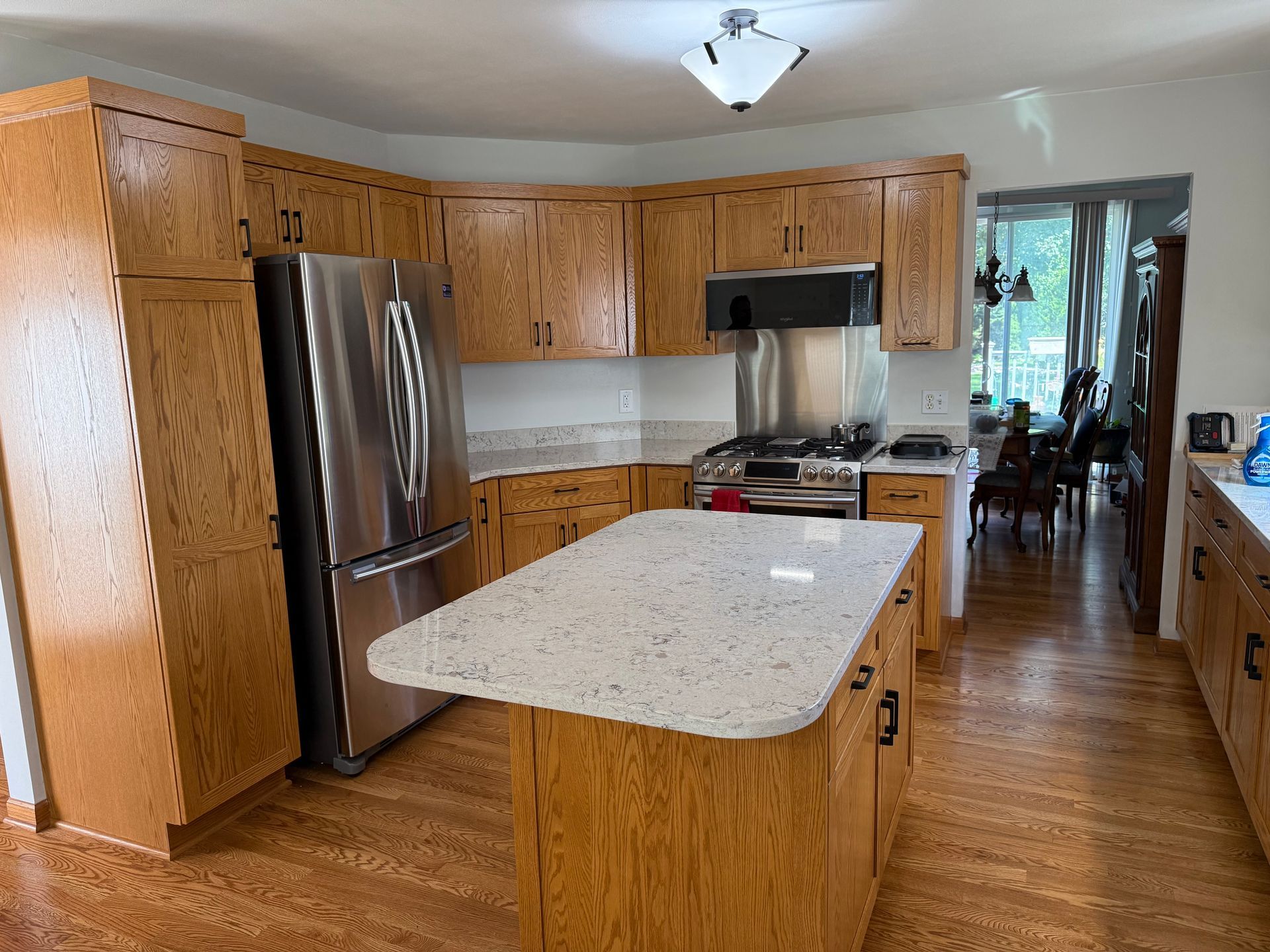 Wooden kitchen with stainless steel appliances, white island, and hardwood floors