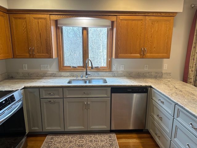 Kitchen with wood cabinets, white countertops, stainless dishwasher, and a window above the sink.