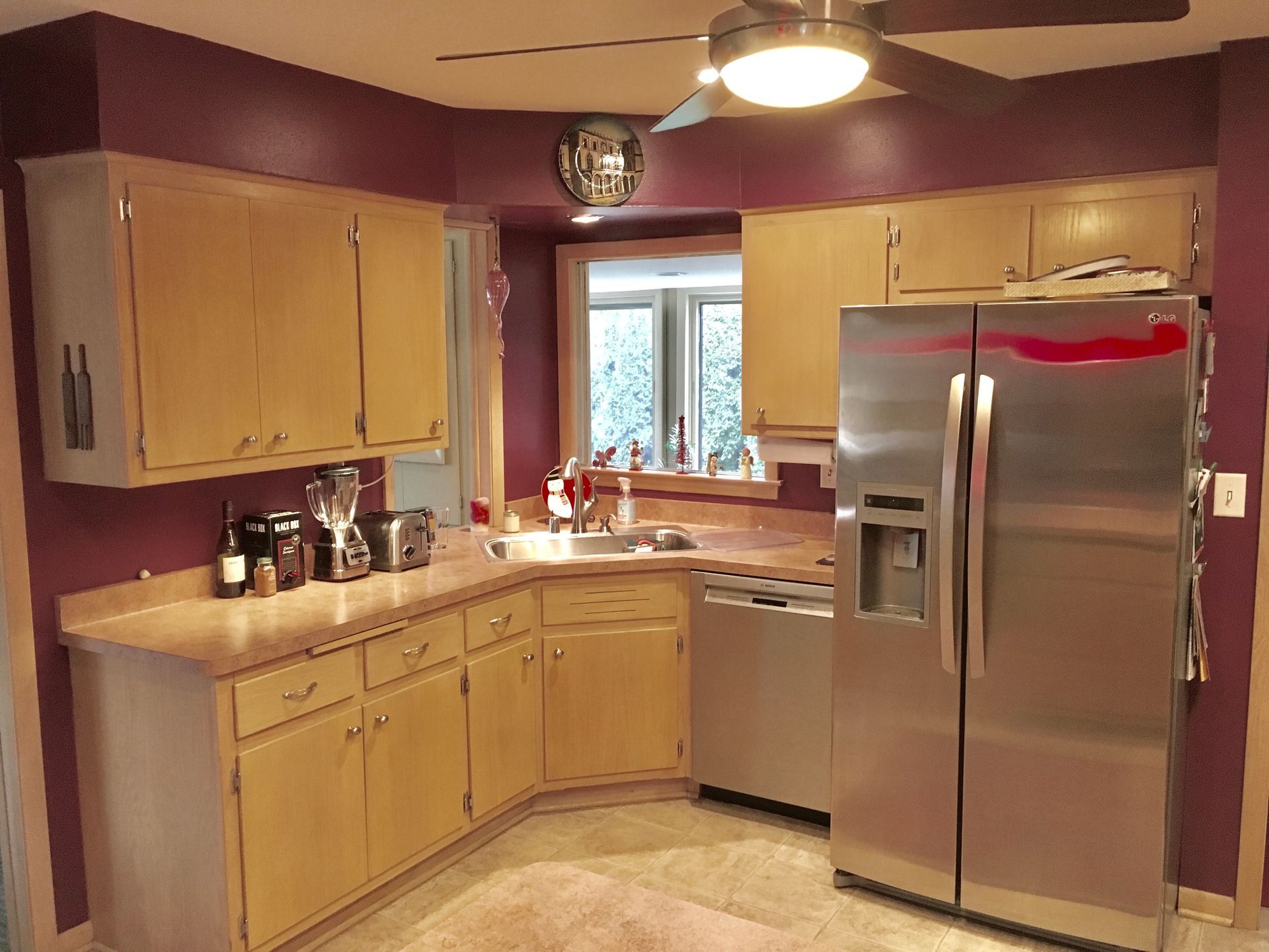 Bright kitchen with light wood cabinets, stainless steel fridge, and a window over the sink.