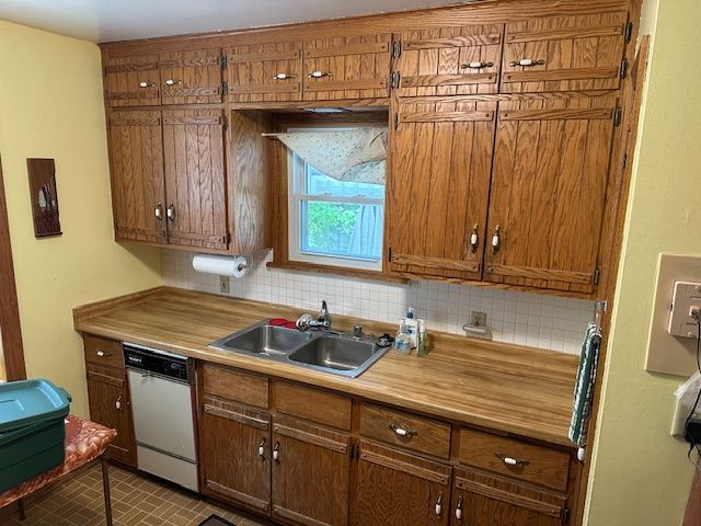 Kitchen with wooden cabinets, butcher-block counters, stainless sink, dishwasher, and a window above the sink.
