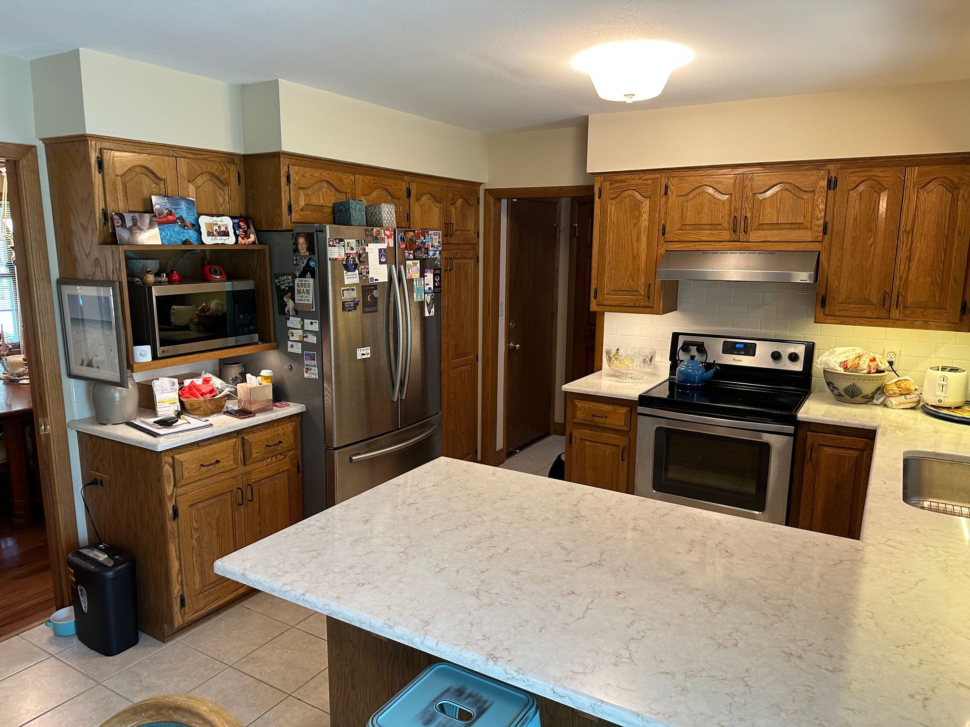 Spacious kitchen with wood cabinets, stainless steel appliances, and a white island countertop