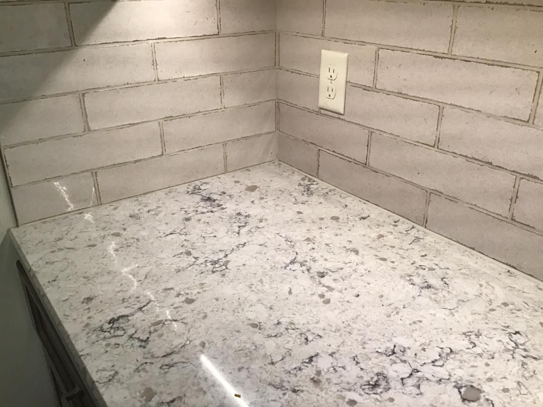 Empty countertop against cinder block wall with a wall outlet