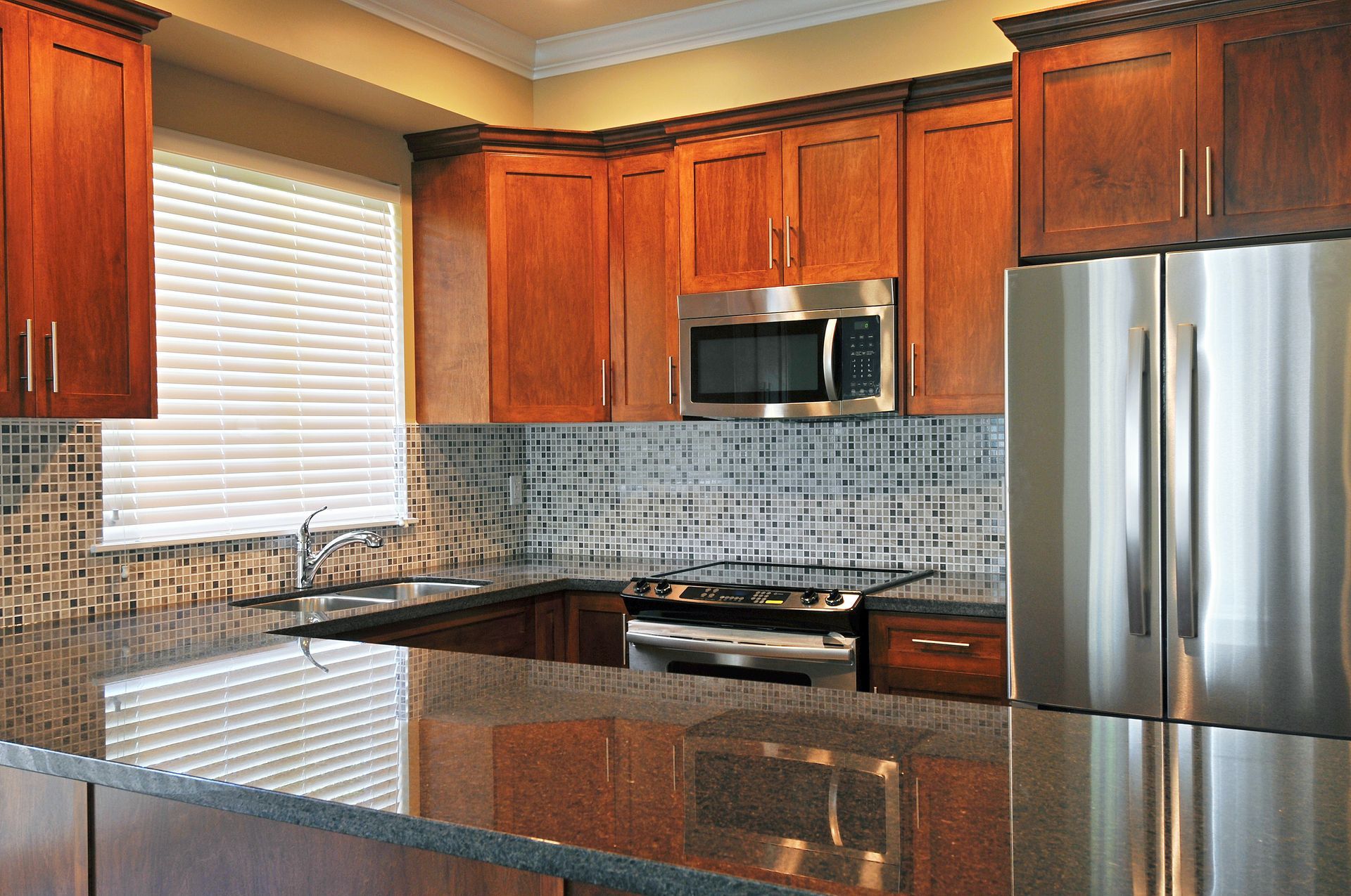 A modern kitchen in Franklin, WI, featuring a refrigerator, stove, sink, and stylish cabinet refacin
