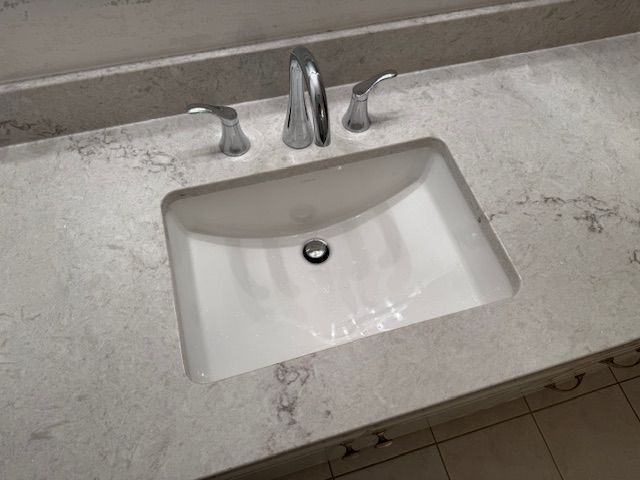 Bathroom sink with chrome faucet and white countertop vanity.