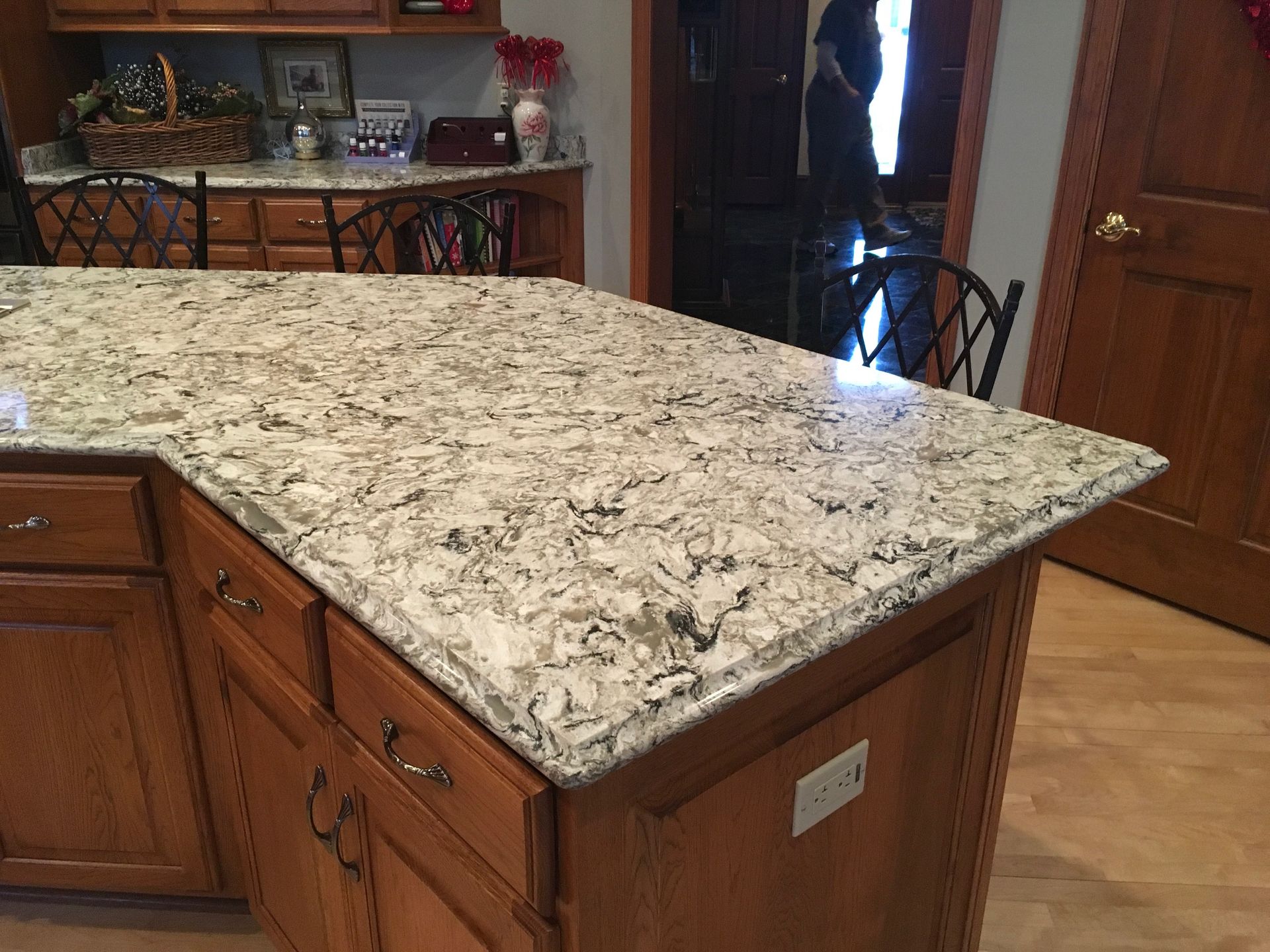 Kitchen island with speckled granite countertop and wooden cabinets, viewed from the side.