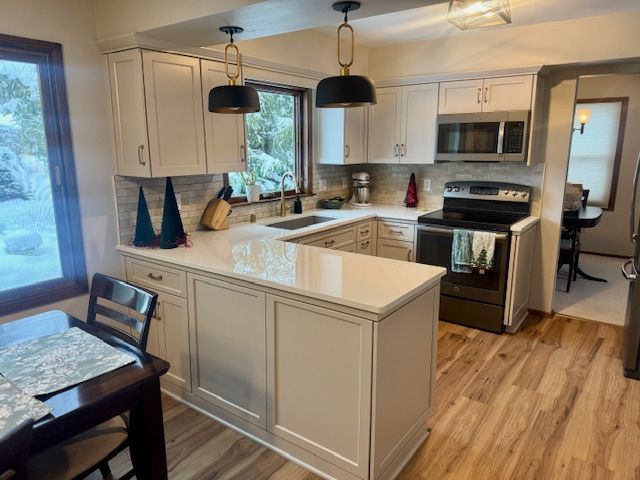 Bright kitchen with white cabinets, central island, hardwood floors, and stainless steel appliances