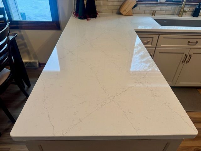 White quartz kitchen island countertop with beige cabinets and a window in the background