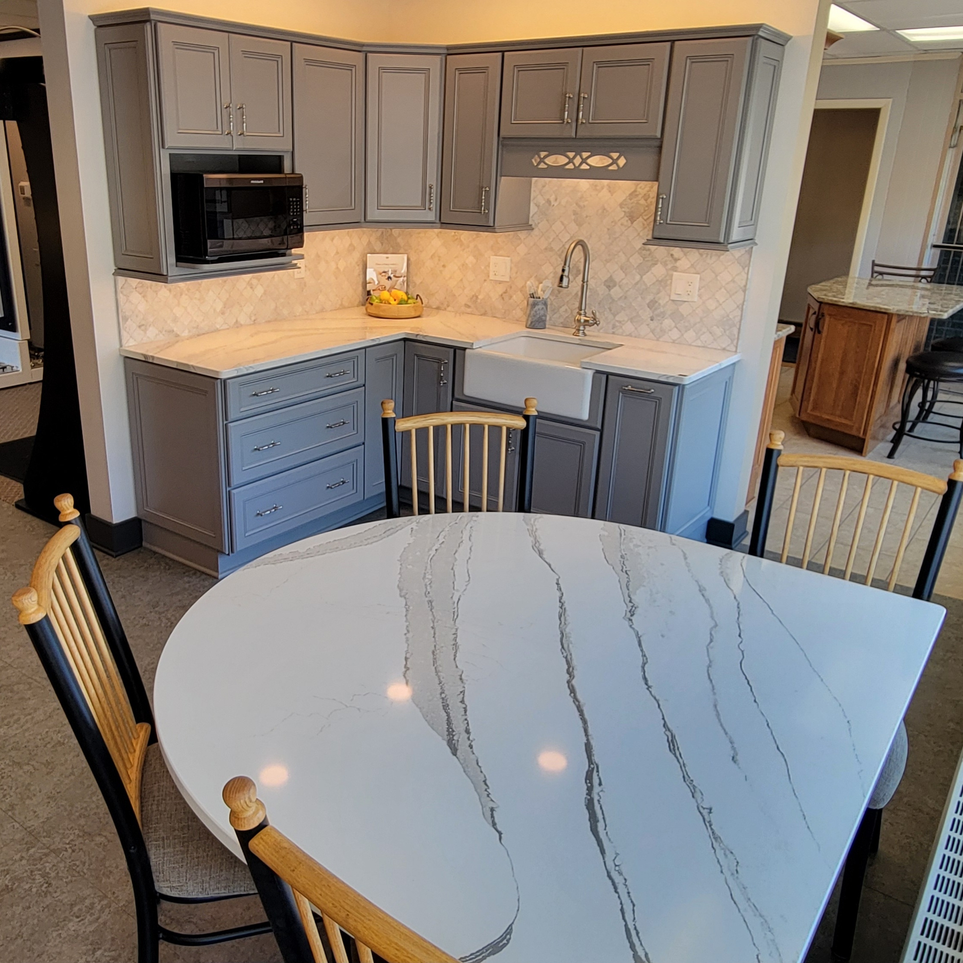 Modern kitchen with gray cabinets, marble-look countertops, and a white dining table in the foreground