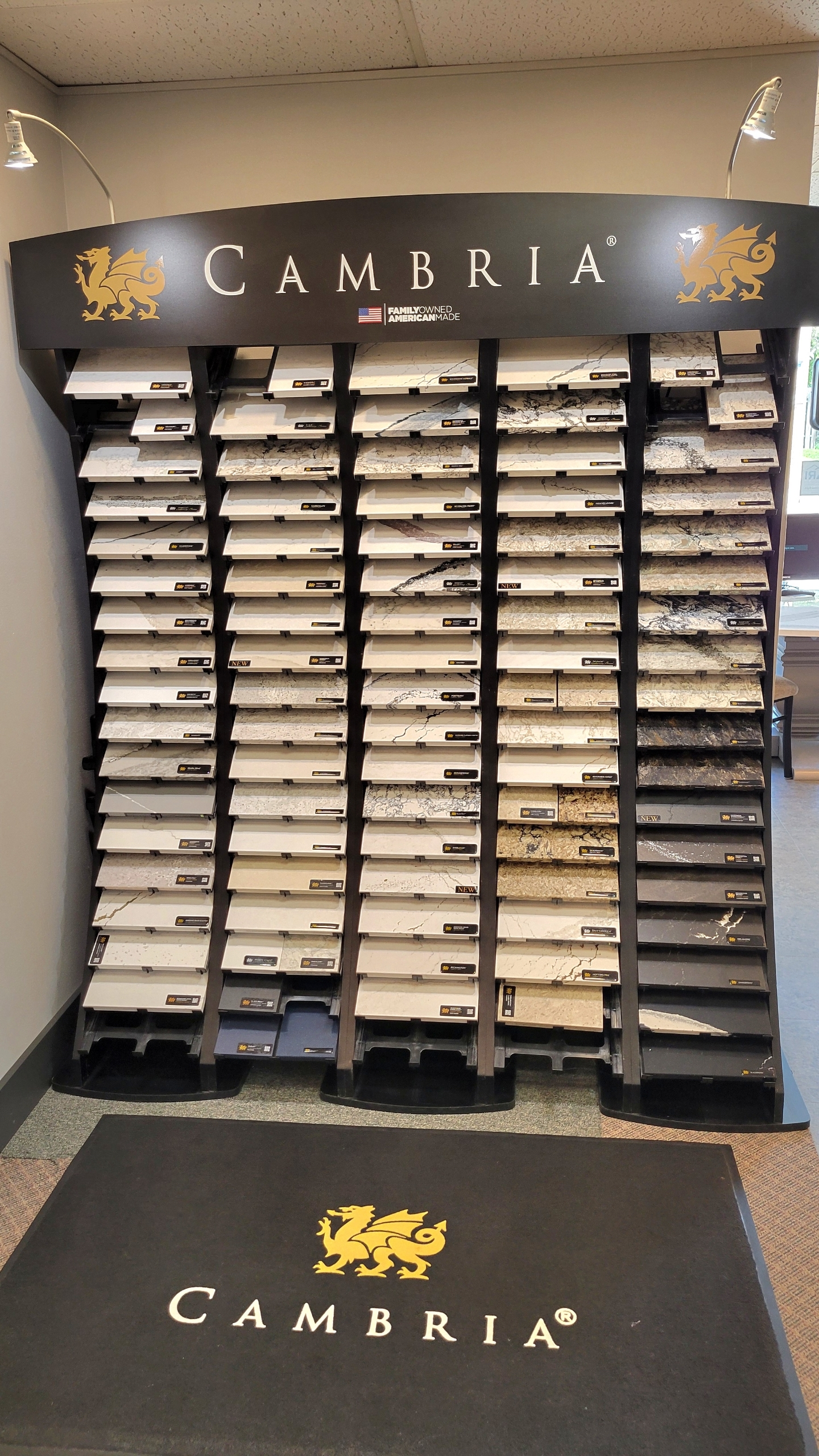 Cambria stone display wall with sample slabs and branded floor mat in a showroom