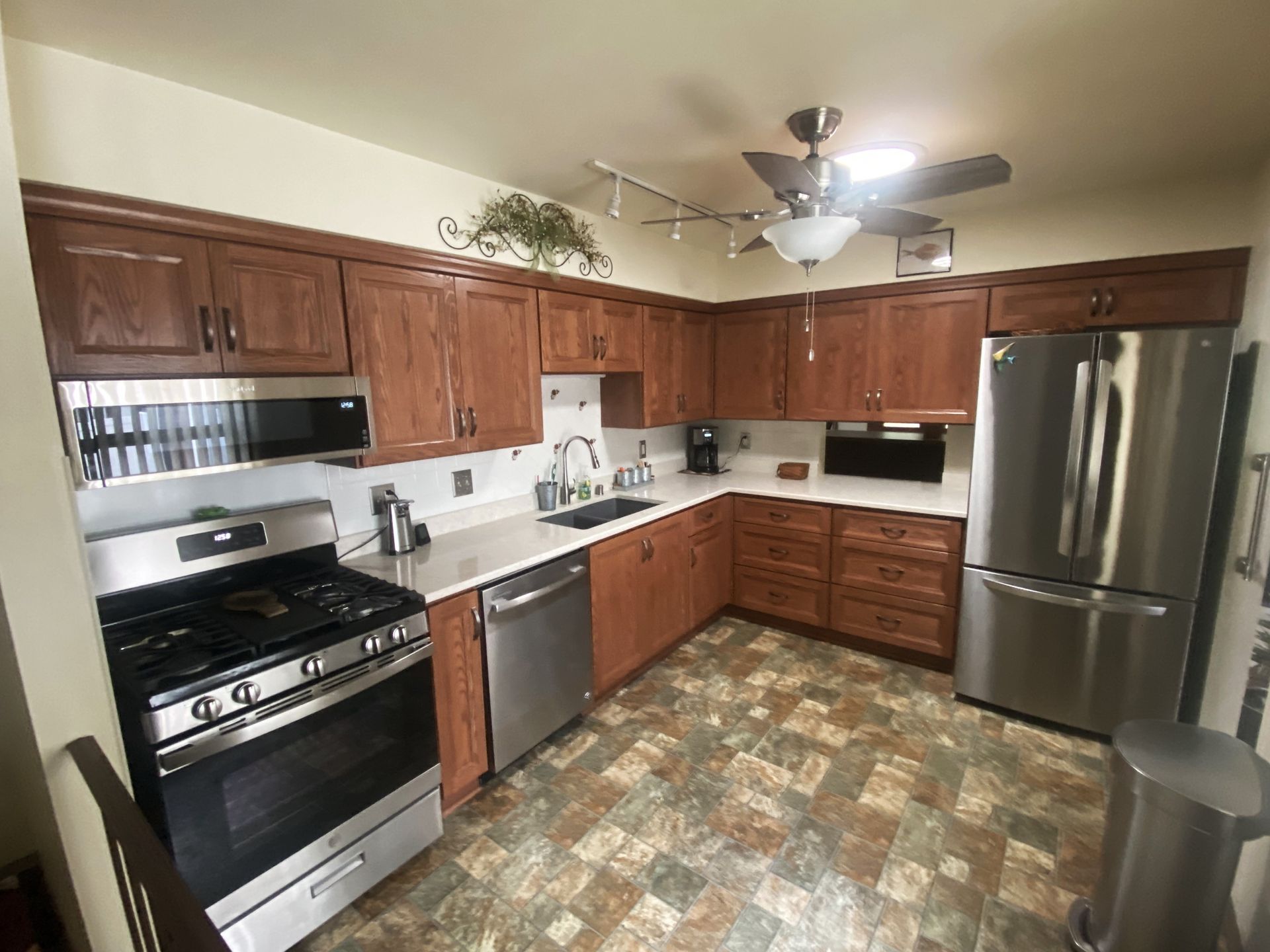 Kitchen with brown cabinets, stainless steel appliances, and patterned flooring.