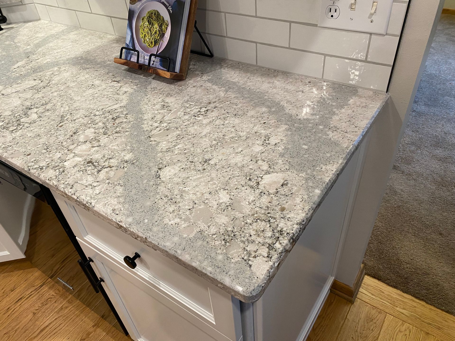 Gray speckled granite countertop on a white kitchen island with a display frame on top
