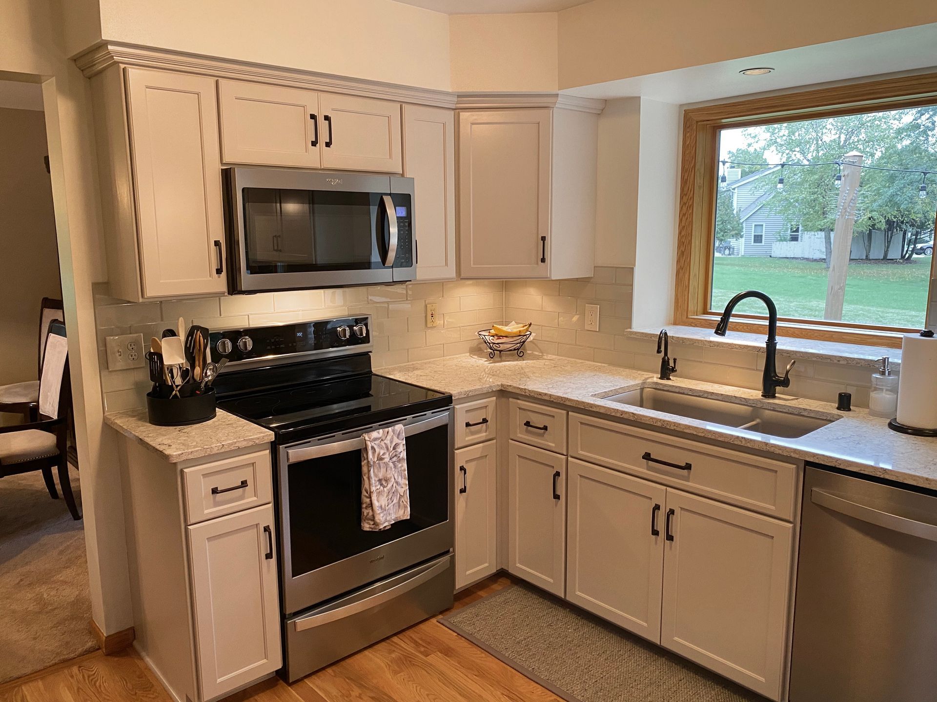 Bright kitchen with stainless steel appliances, white cabinets, granite counters, and a window over the sink.
