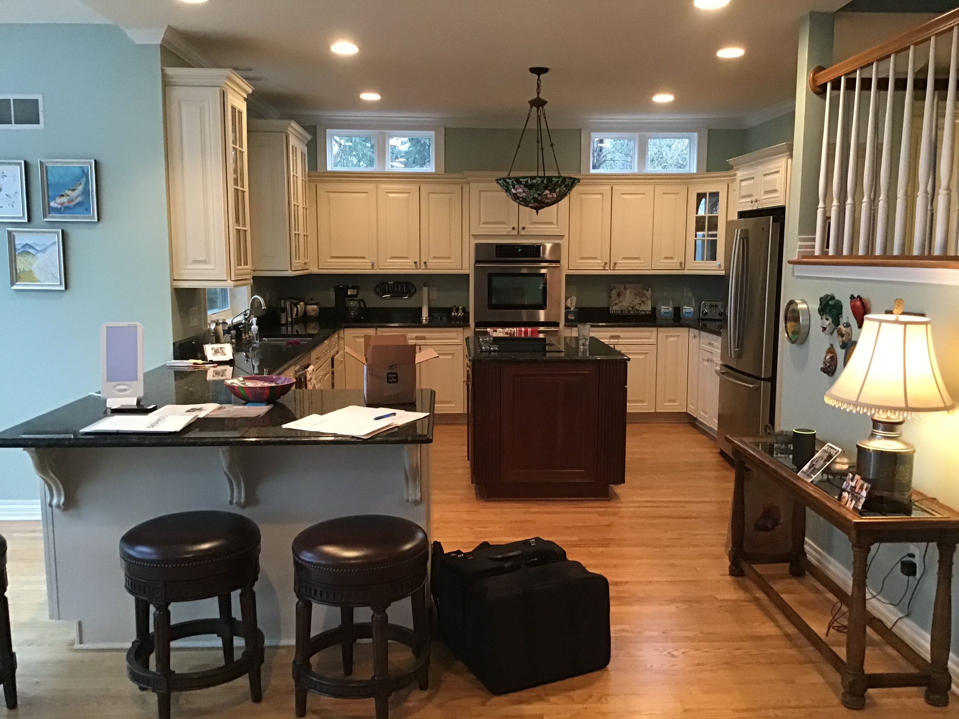 Bright kitchen and dining area with island, stools, cabinets, and warm lighting