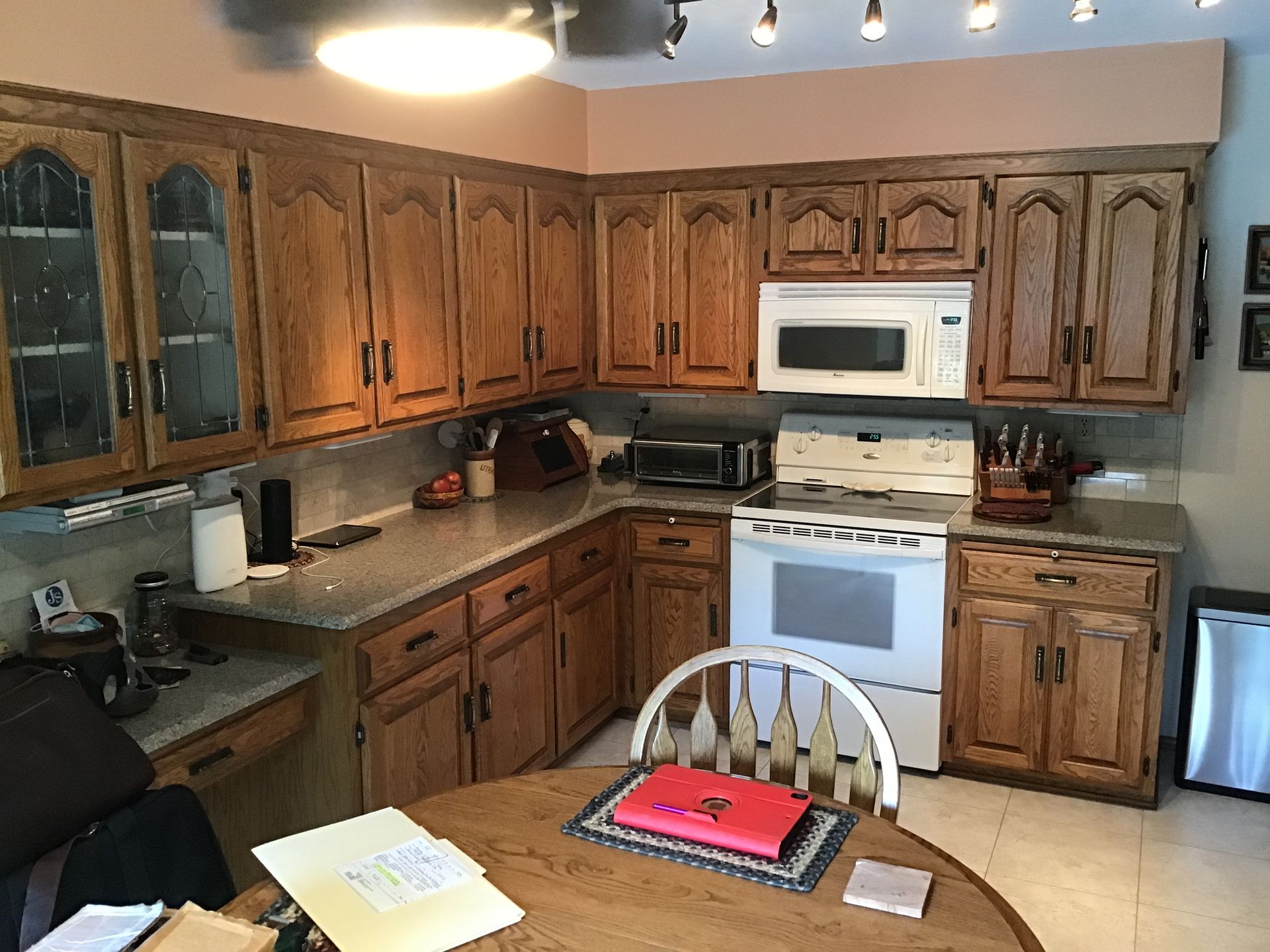 Kitchen with wooden cabinets, white appliances, and a table in the foreground.