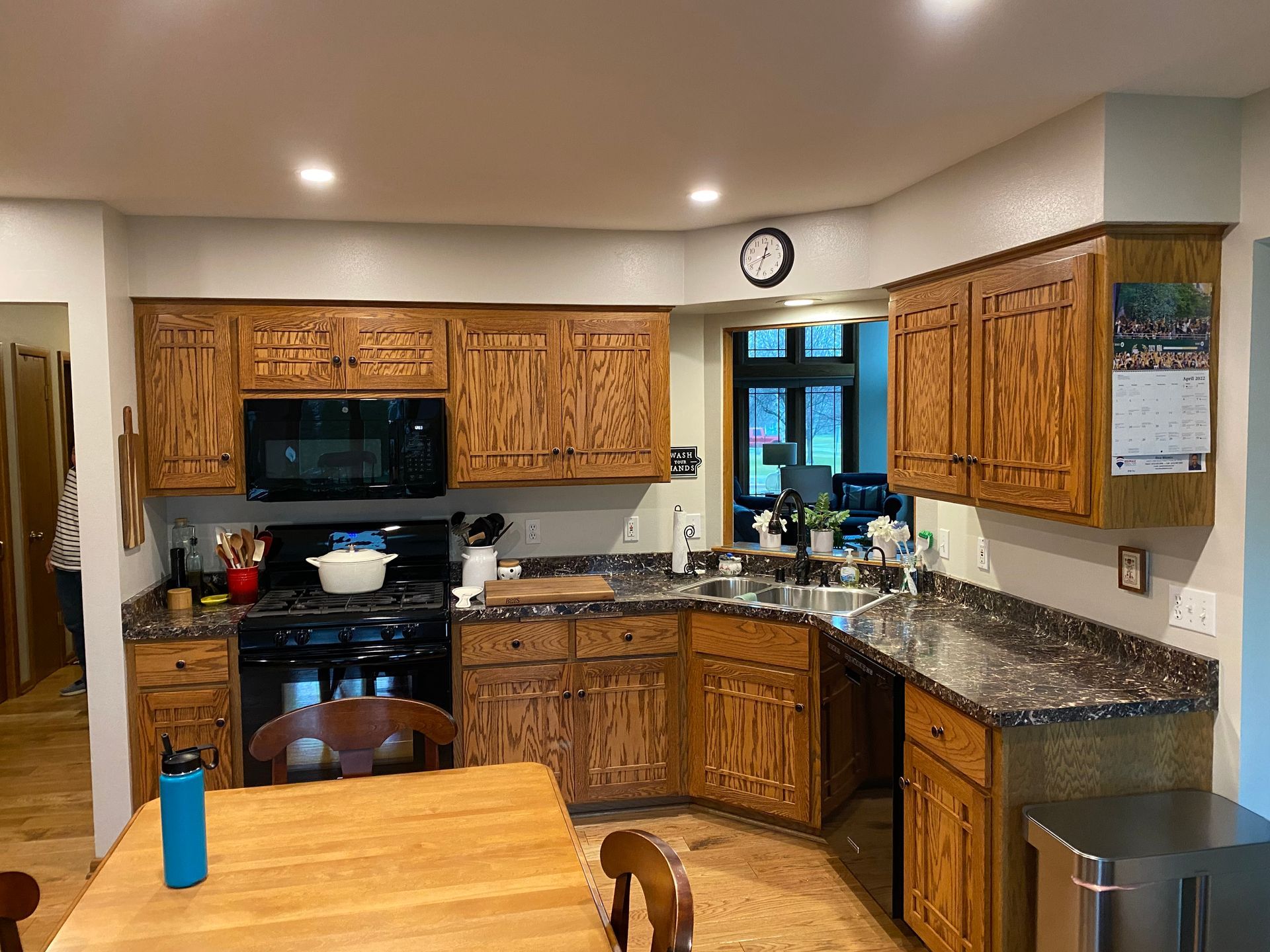 Kitchen with wooden cabinets, granite counters, black appliances, and a small table in the foreground.