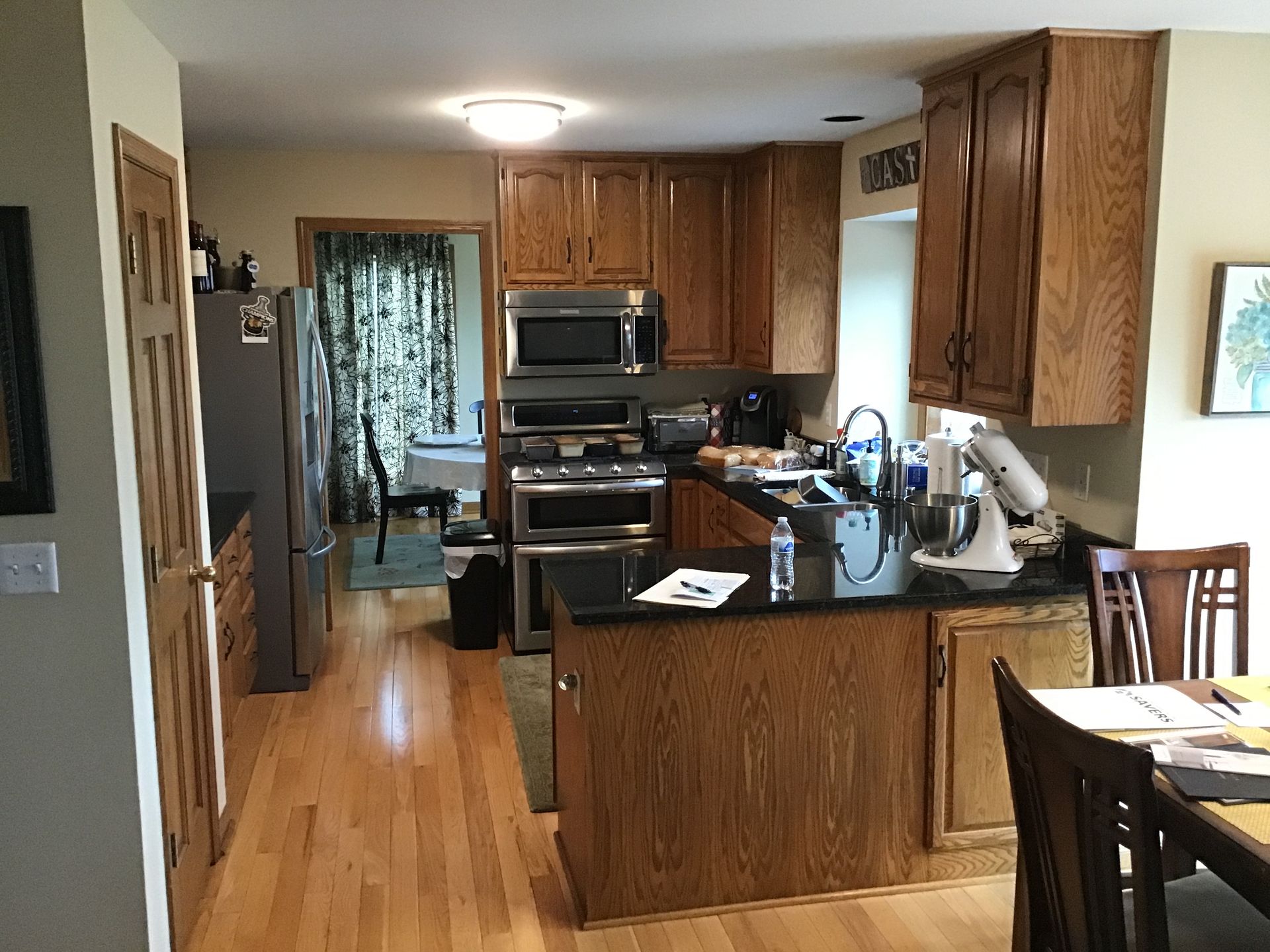 Kitchen with wooden cabinets, black countertops, stainless appliances, and a dining table in the foreground