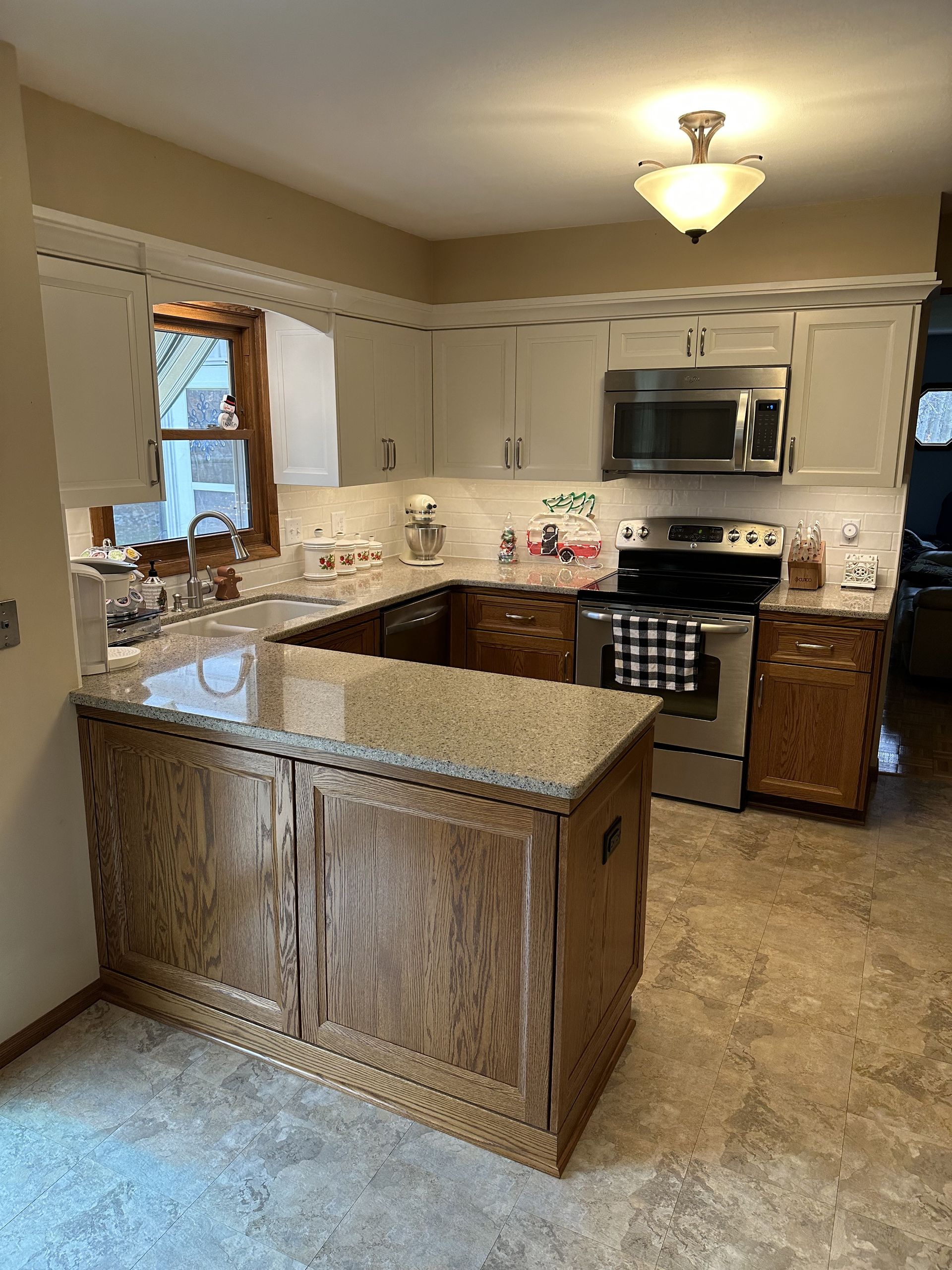 Bright kitchen with white cabinets, granite island, stainless stove, and wood floors