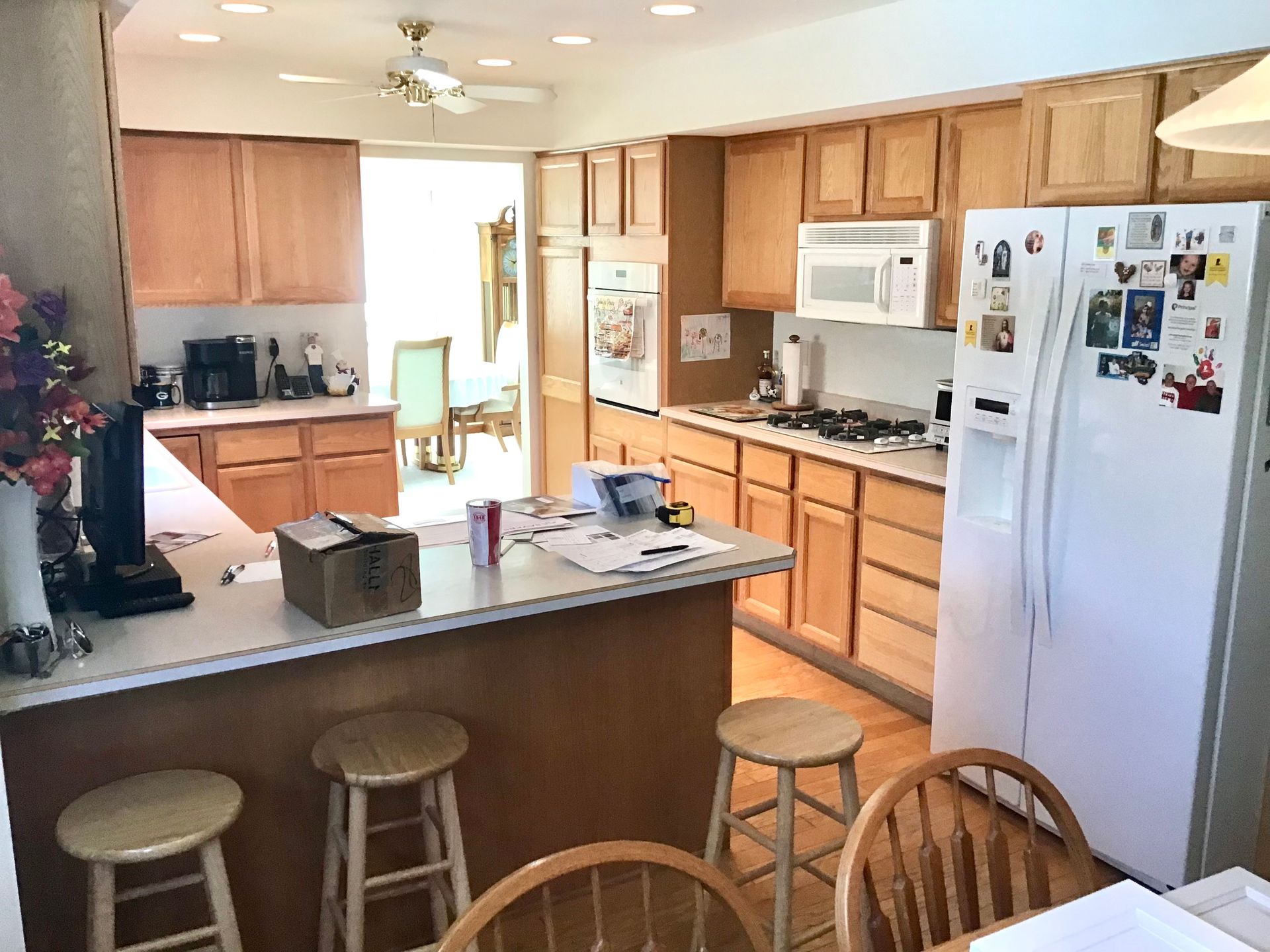 Bright kitchen with wooden cabinets, white appliances, and a central island with stools.