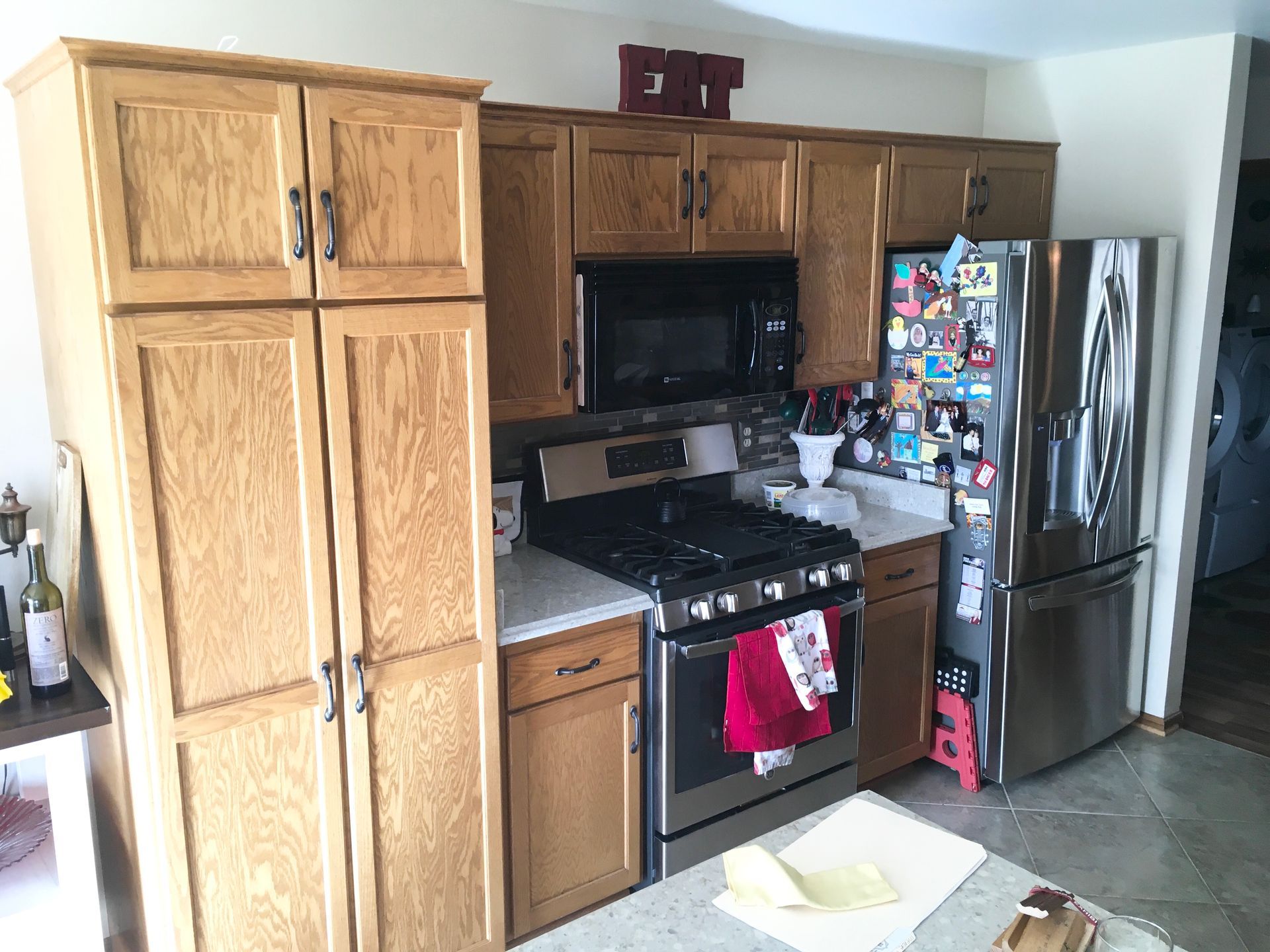 Kitchen with oak cabinets, stainless fridge, black stove, and a white island in the foreground