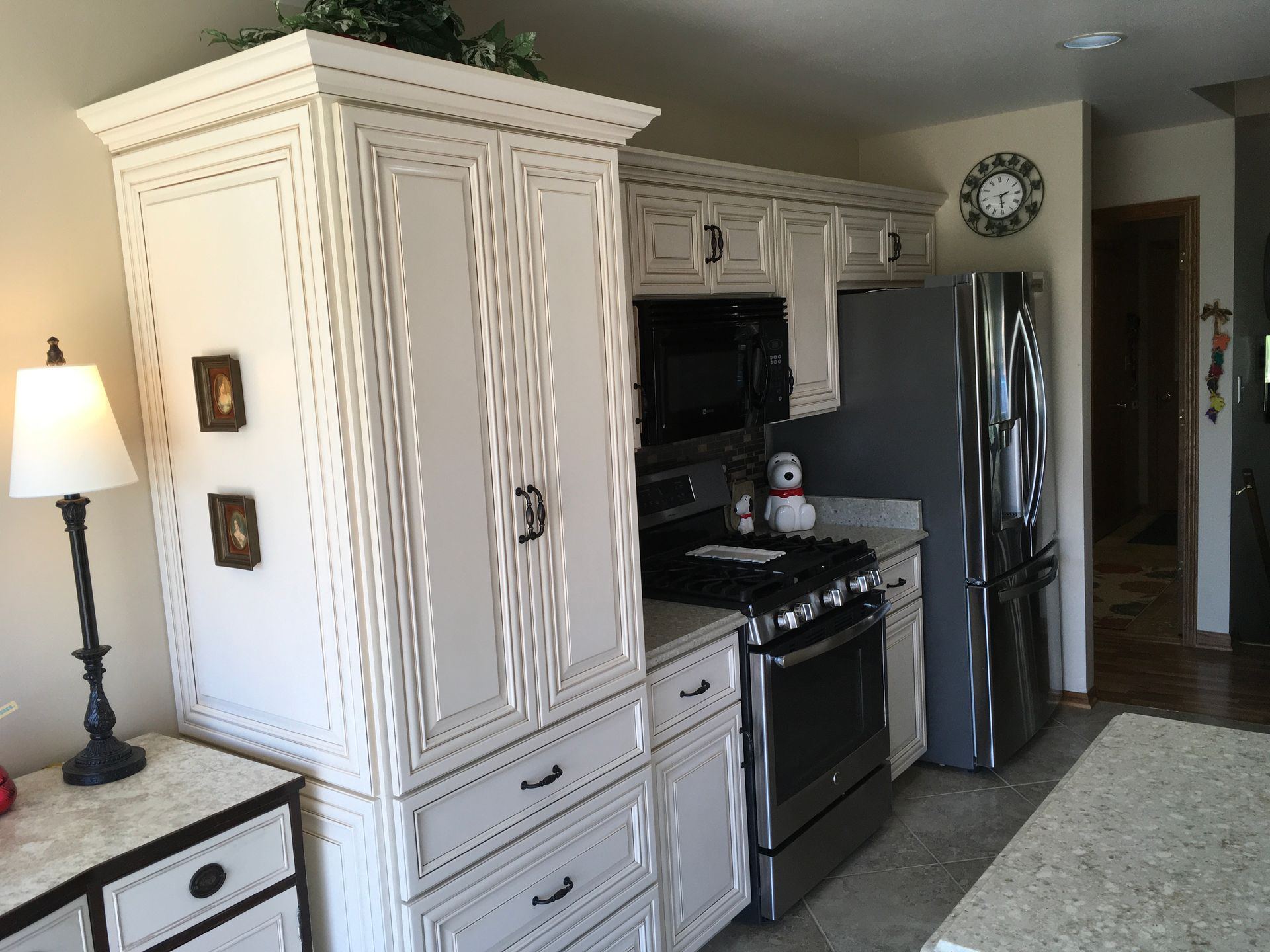 Kitchen with white cabinets, black stove, stainless fridge, and beige rug in a bright home interior
