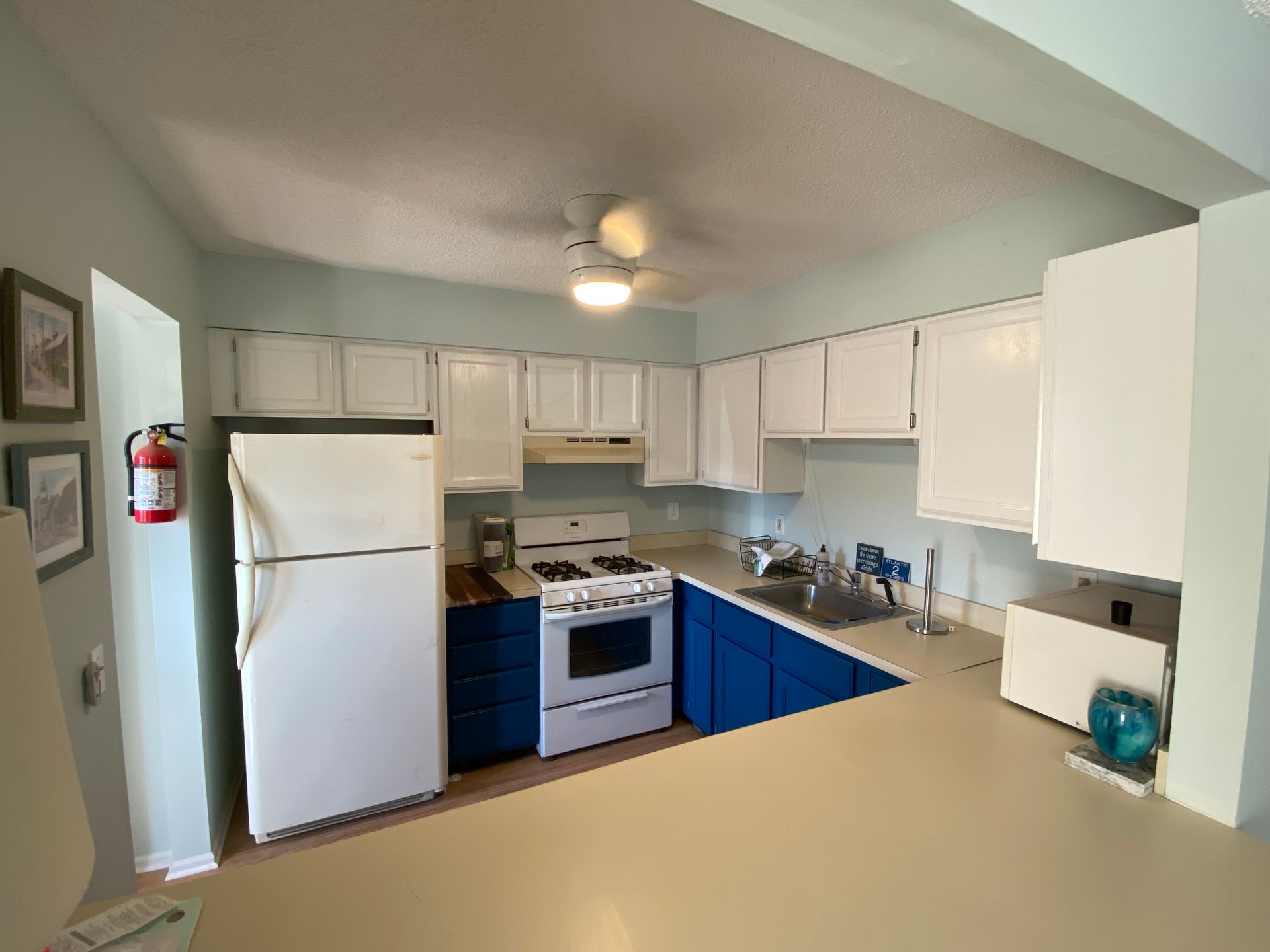 Kitchen with white cabinets, blue base cabinets, refrigerator, and stove.