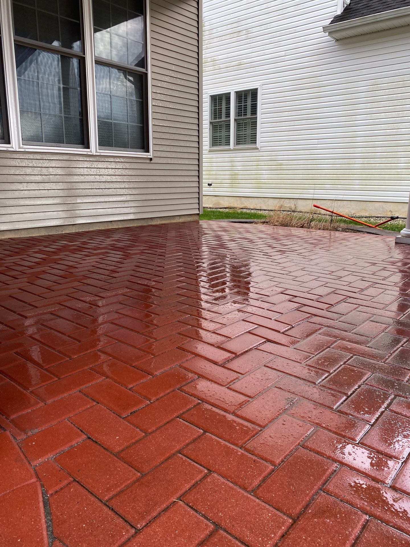 Red brick patio with a herringbone pattern; reflects the building and sky.