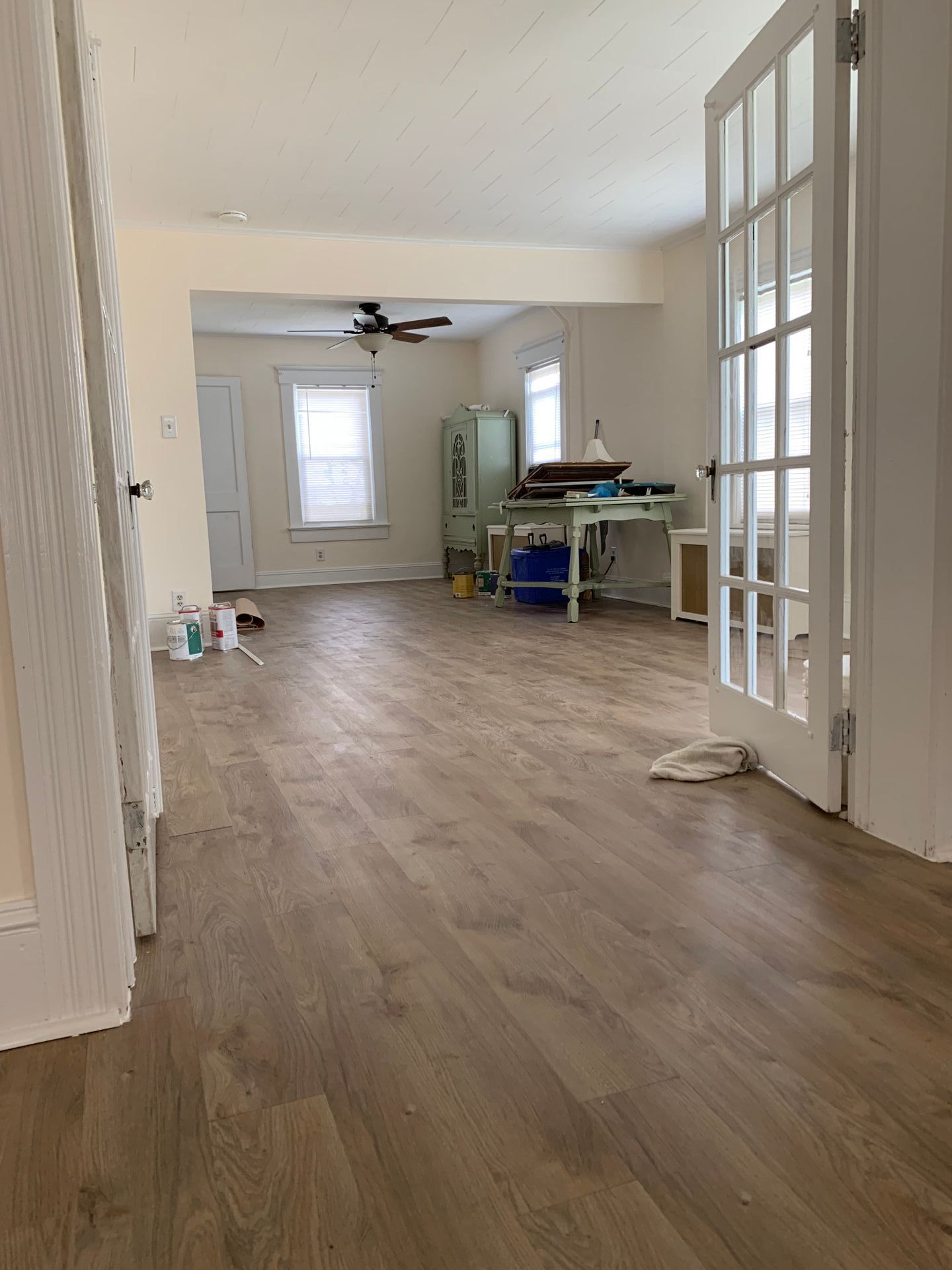 Interior view of a room with wood-look flooring, french doors, a work table, and windows.