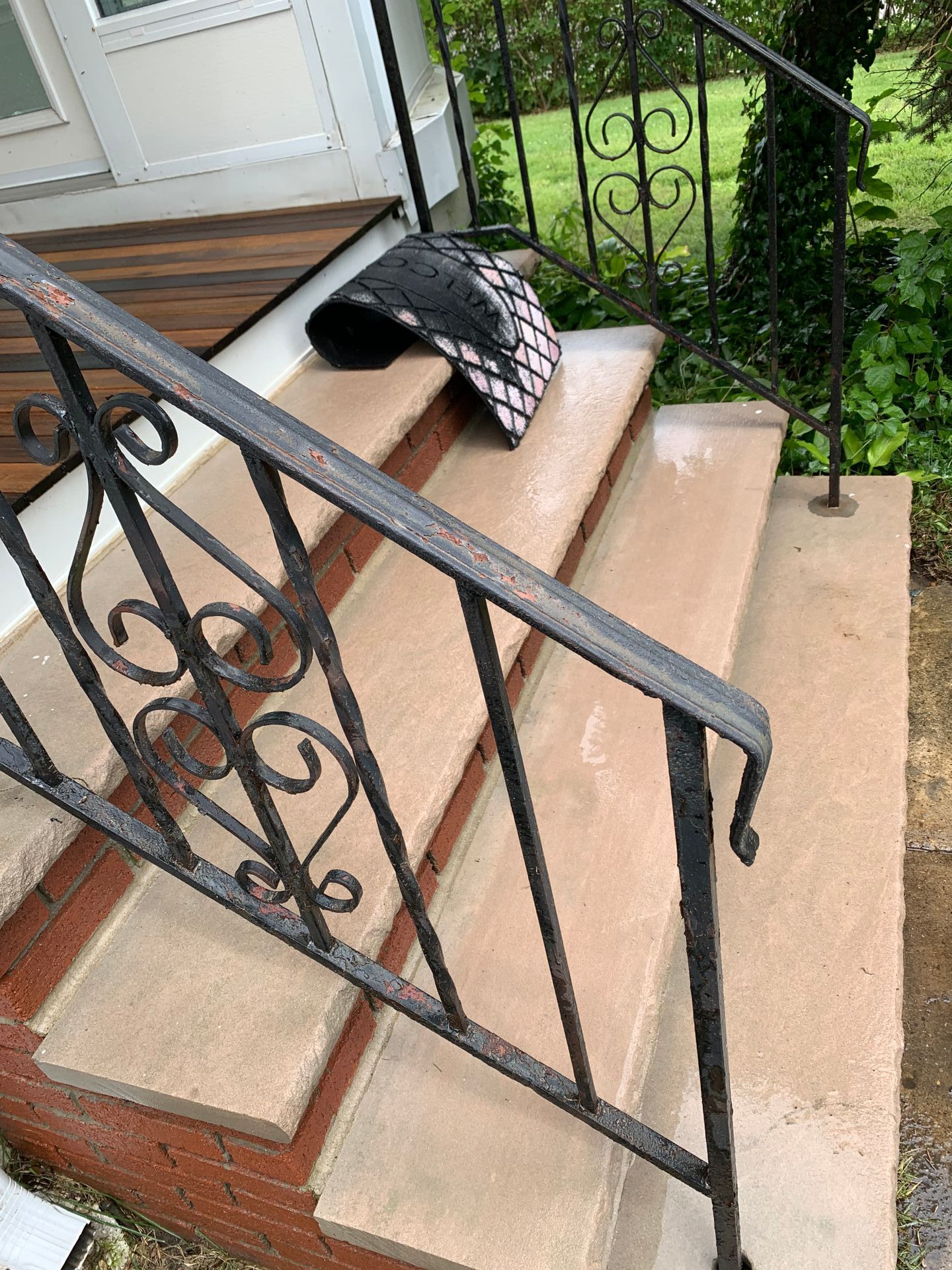 Concrete steps with a wrought-iron railing leading to a doorway. A bag rests on the top step.
