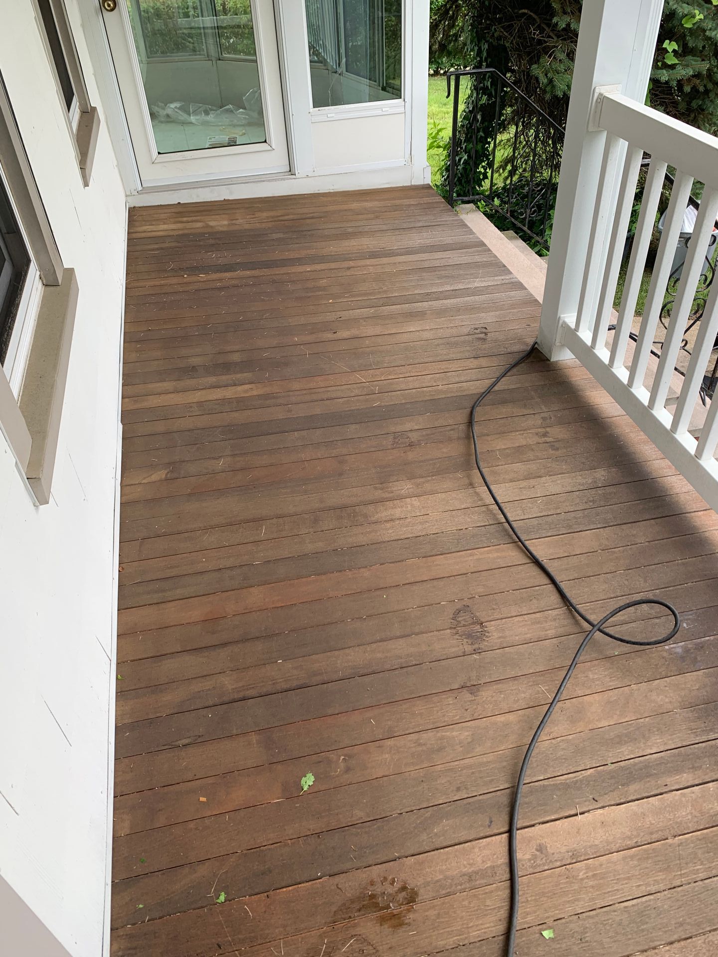 Wooden deck with visible weathering, a black cord, and a white railing.