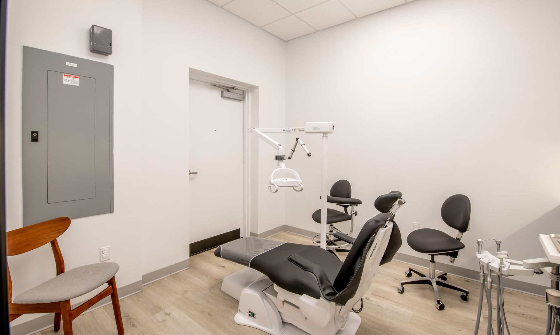 Dental office room with a chair, tools, and a gray electrical panel on the wall.