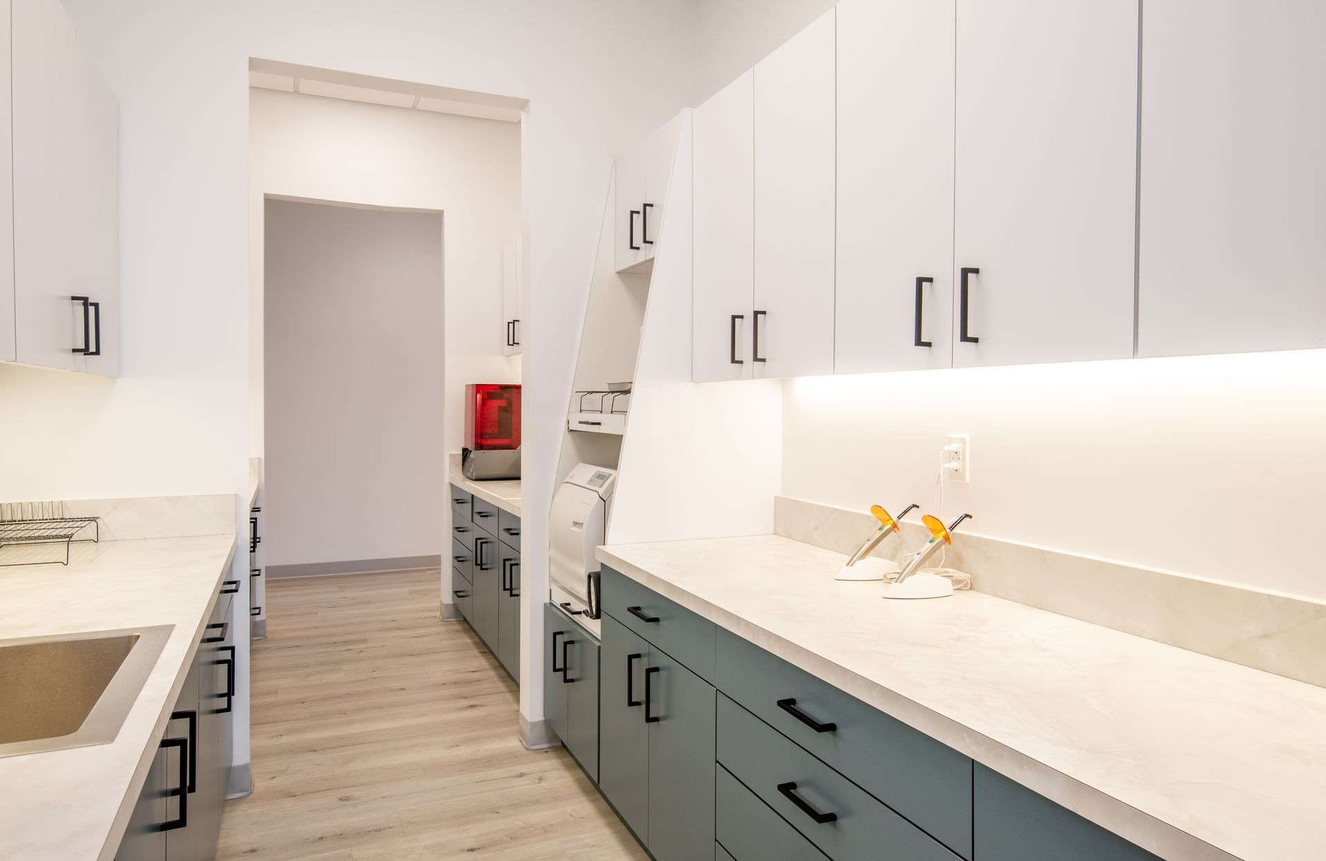 Narrow kitchen with white and teal cabinets, countertops, and a long hallway.