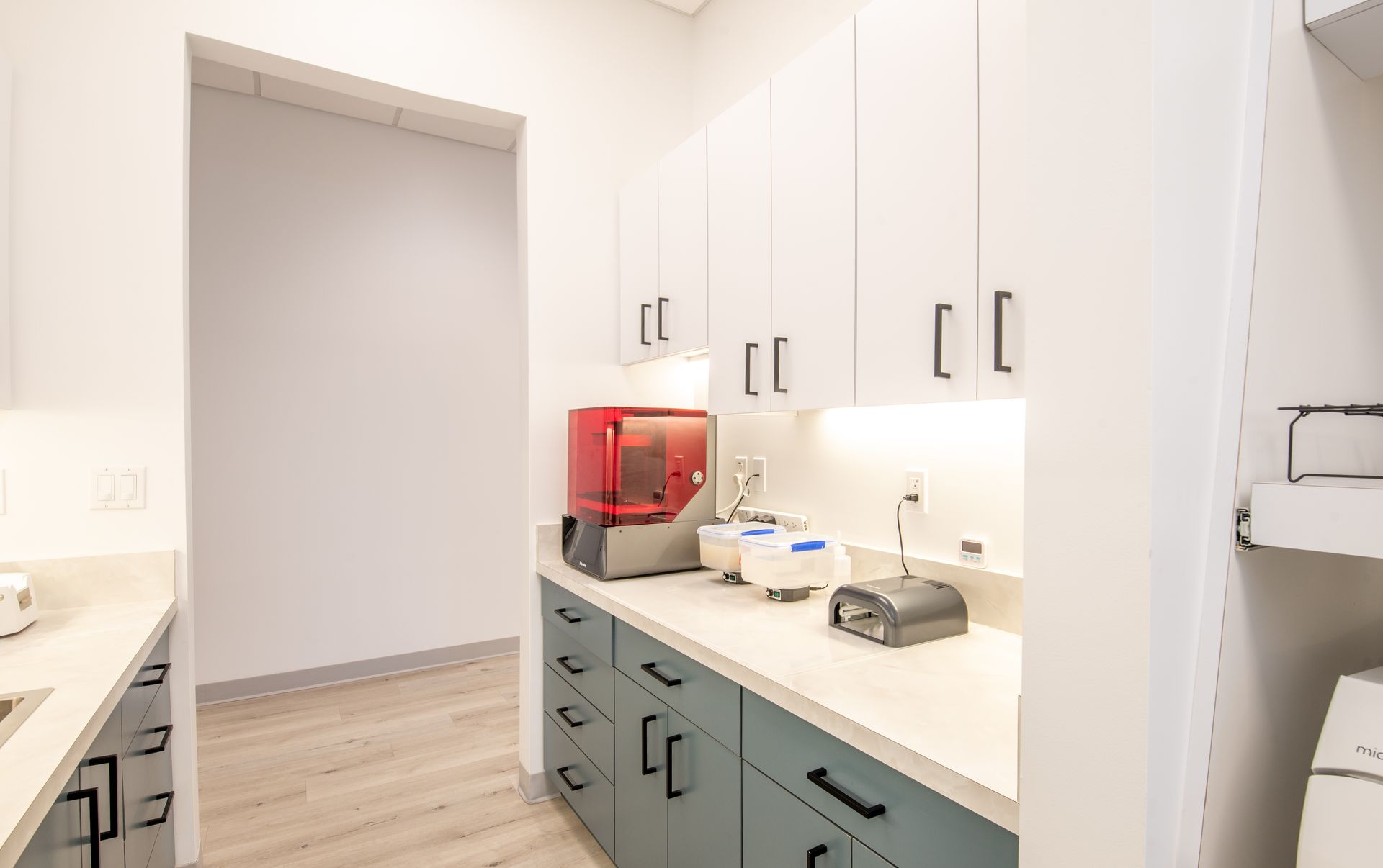 Dental office laboratory with blue and white cabinetry, medical equipment.
